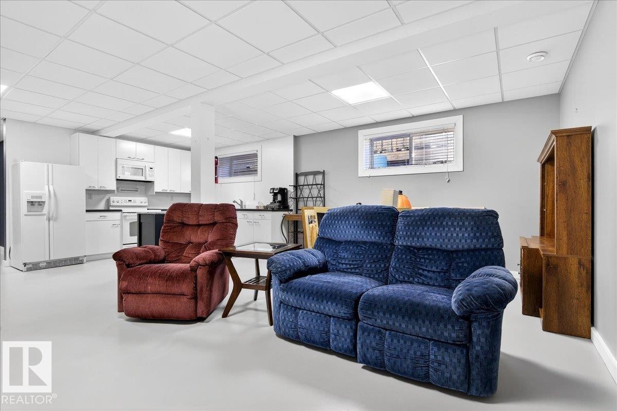 Living area with a paneled ceiling and concrete floors - 5019 48 Avenue, Chipman, AB - Indoor