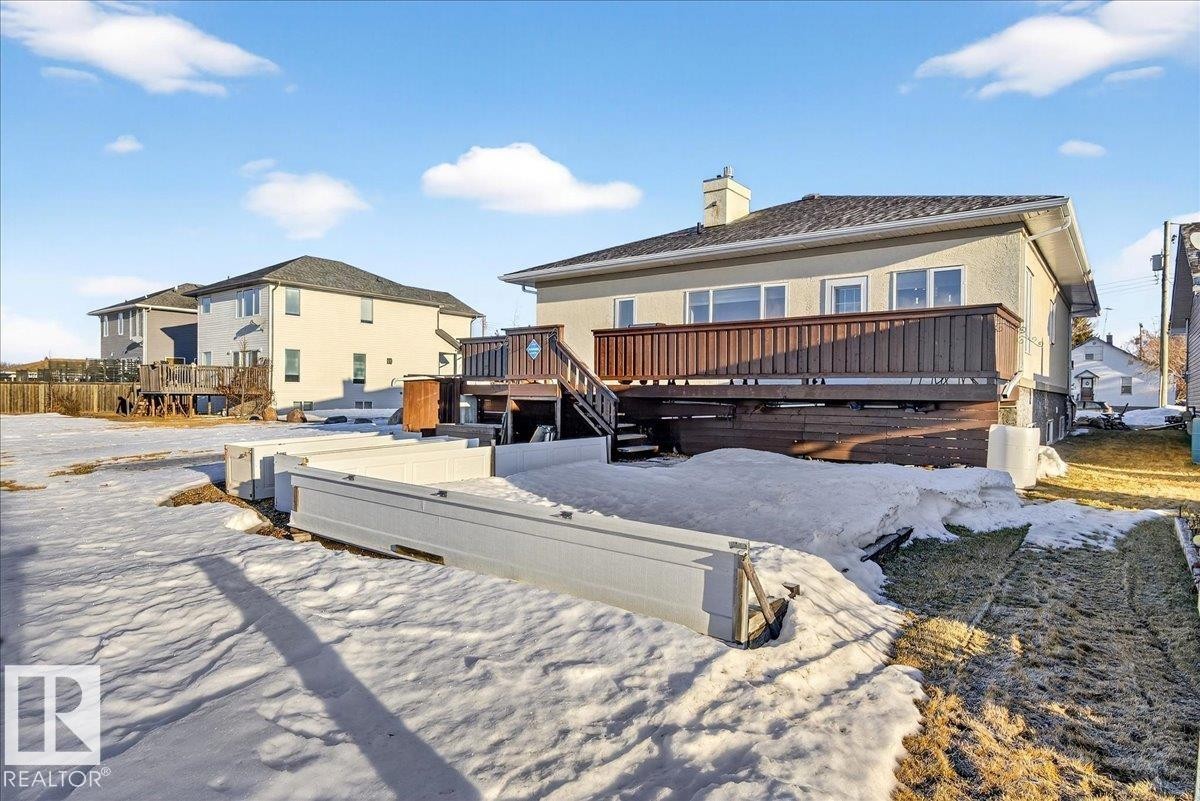Snow covered rear of property with a deck, a residential view, and a chimney - 5019 48 Avenue, Chipman, AB - Outdoor With Deck Patio Veranda