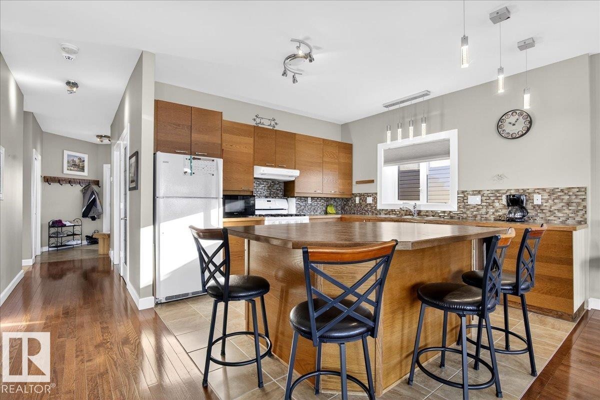 Kitchen with wood finish cabinets, a kitchen breakfast bar, dark countertops, and white appliances - 5019 48 Avenue, Chipman, AB - Indoor