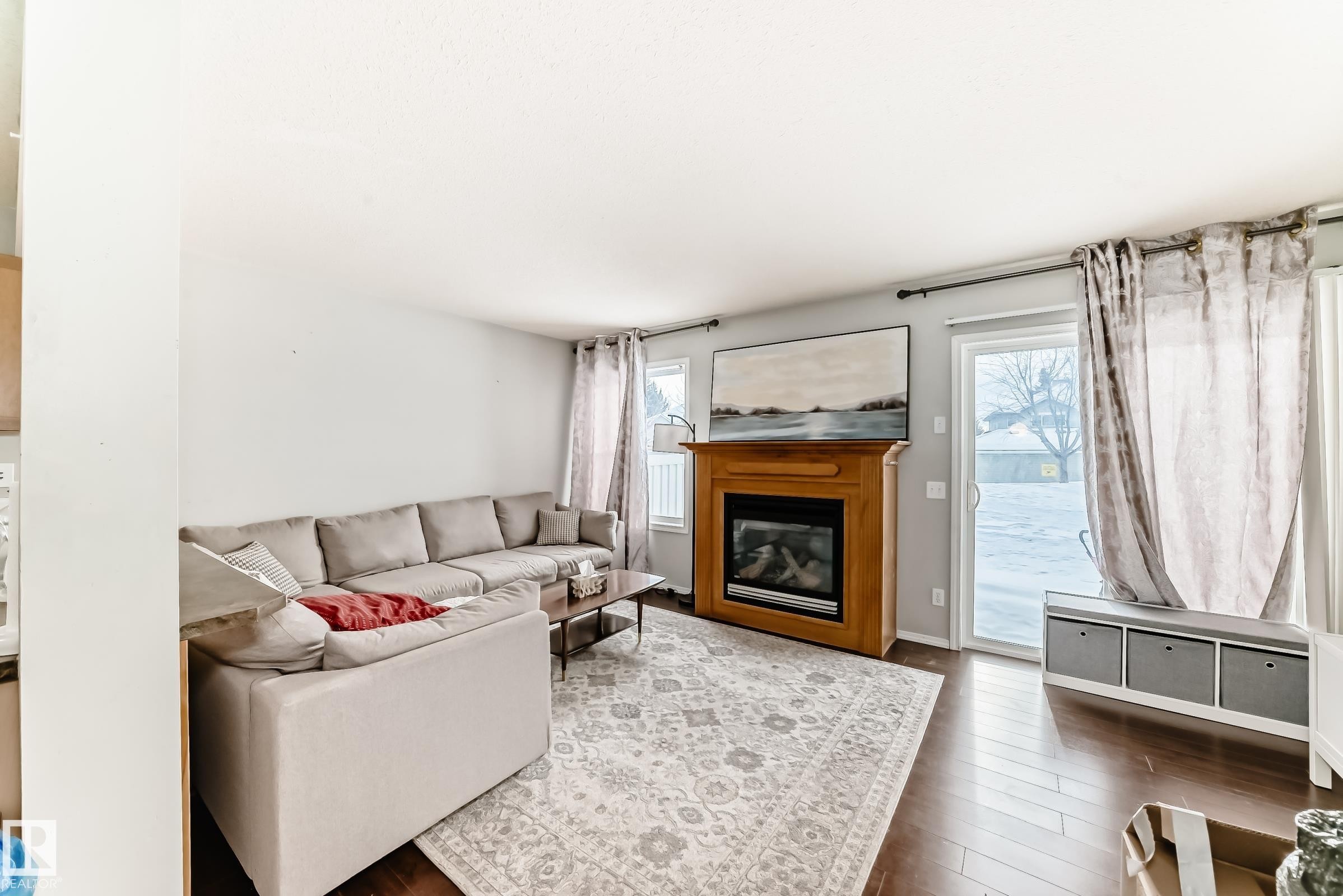 Living room with a glass covered fireplace and dark wood-style floors - 185 230 Edwards Drive, Edmonton, AB