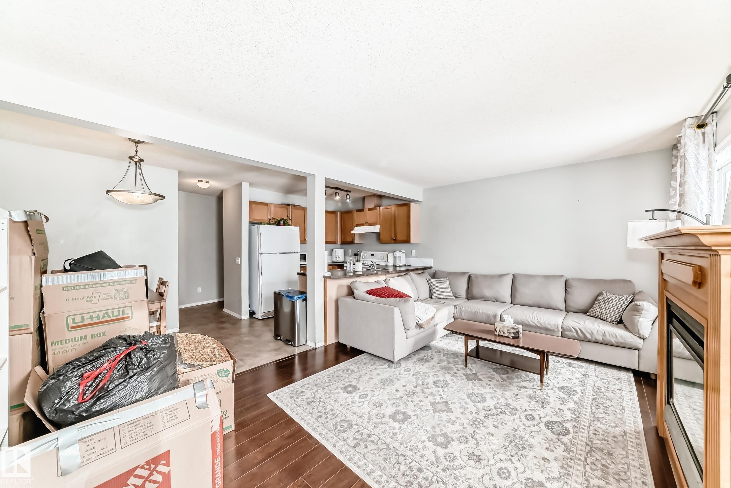 Living room with a fireplace and dark wood-type flooring - 185 230 Edwards Drive, Edmonton, AB