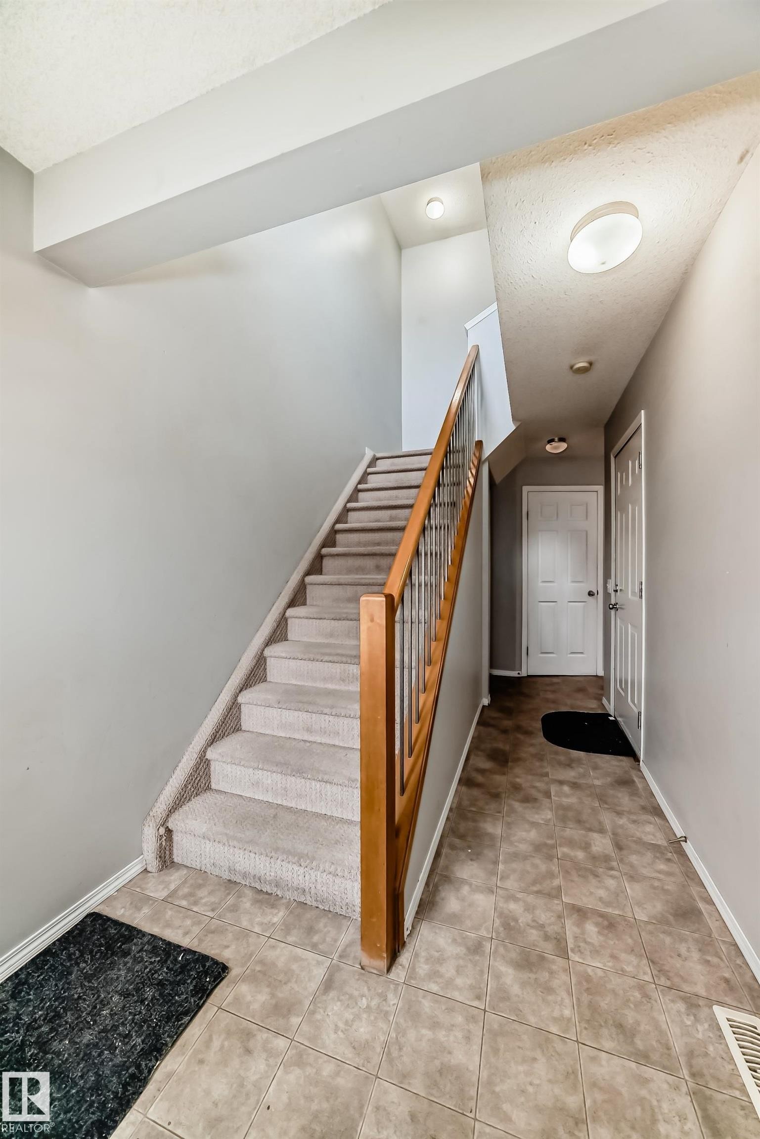 Stairs with a textured ceiling and tile patterned floors - 185 230 Edwards Drive, Edmonton, AB