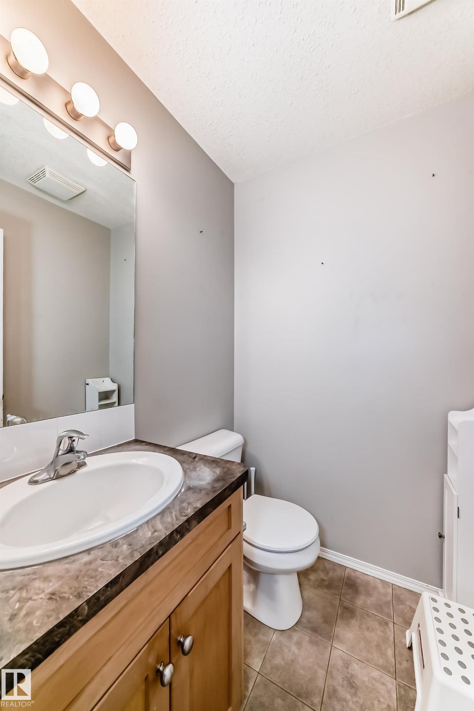 Bathroom featuring vanity, a textured ceiling, and light tile patterned flooring - 185 230 Edwards Drive, Edmonton, AB