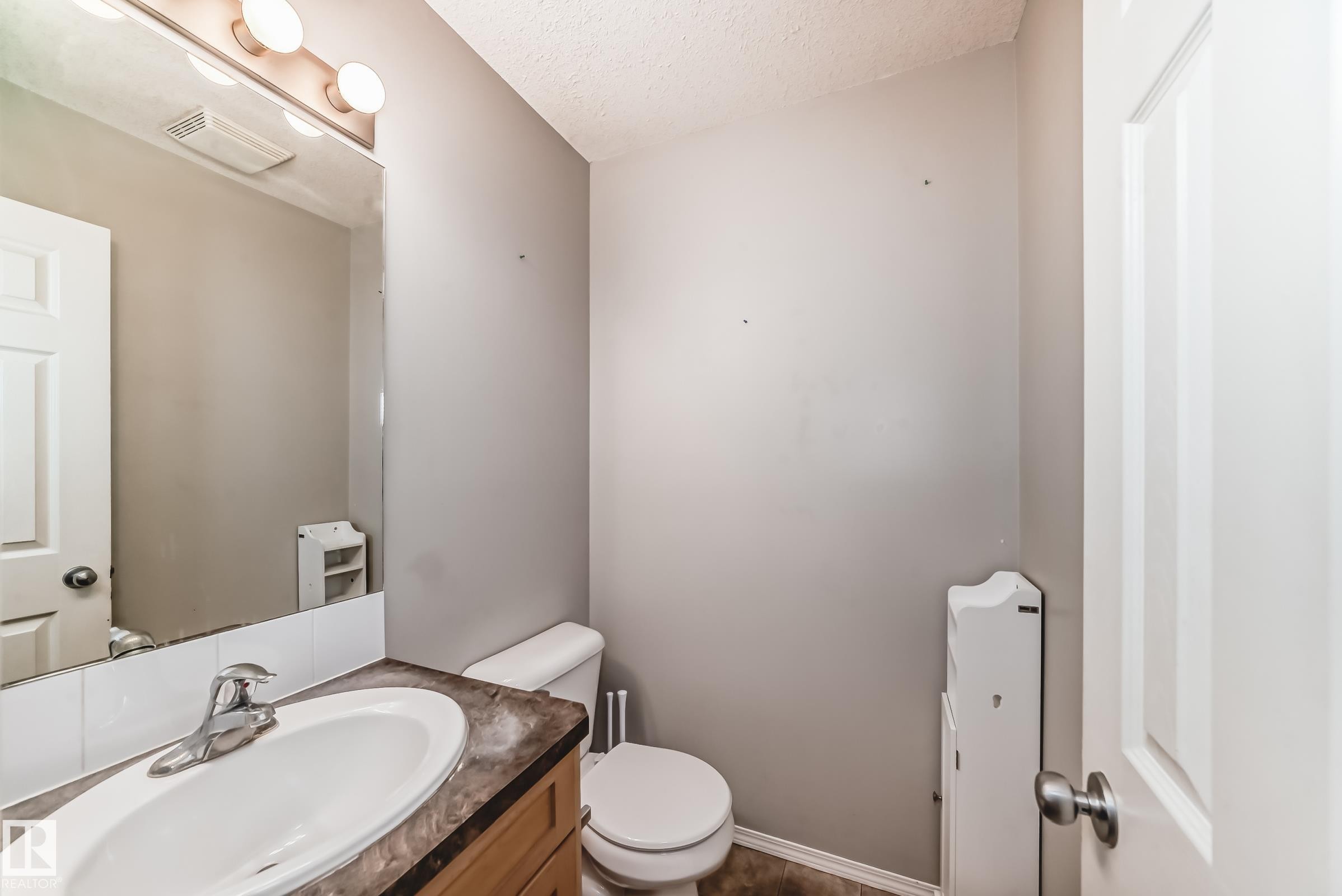 Half bath with vanity and a textured ceiling - 185 230 Edwards Drive, Edmonton, AB