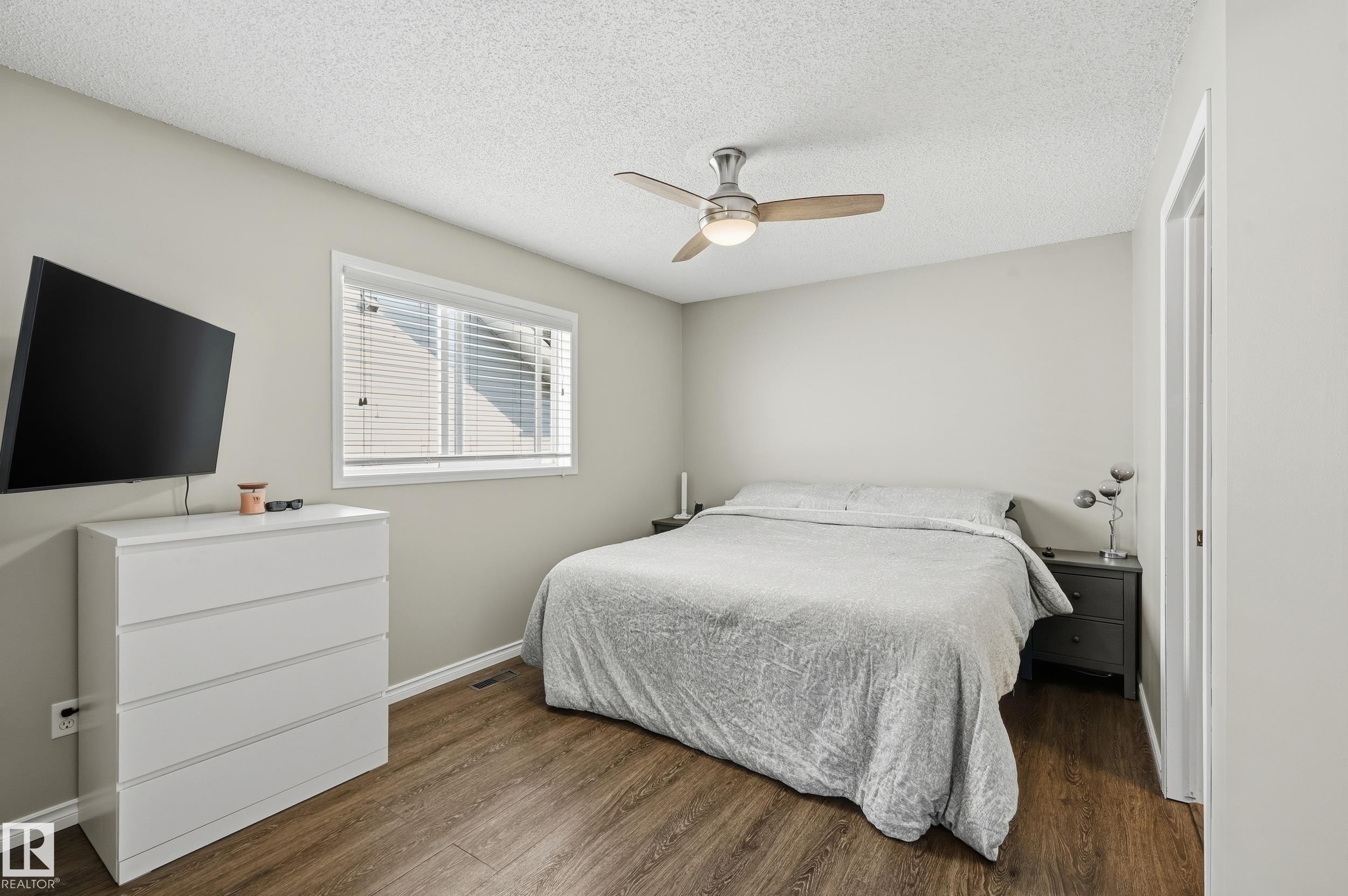 Bedroom with dark wood-style flooring, a textured ceiling, and ceiling fan - 2952 39 Avenue, Edmonton, AB - Indoor Photo Showing Bedroom