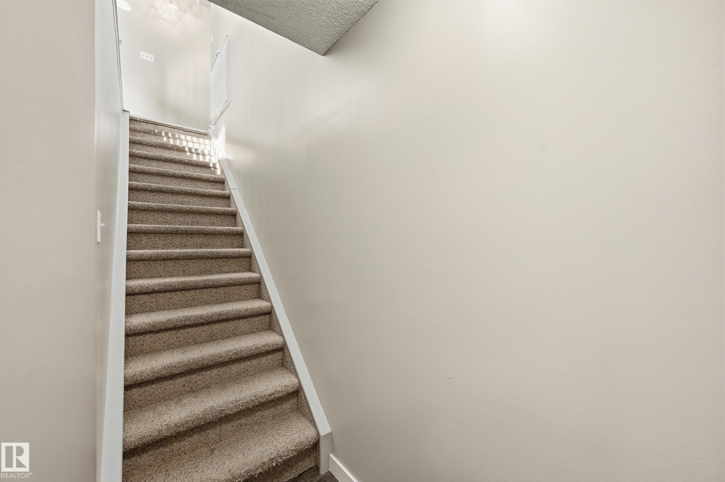 Stairs featuring a textured ceiling and baseboards - 2952 39 Avenue, Edmonton, AB - Indoor Photo Showing Other Room