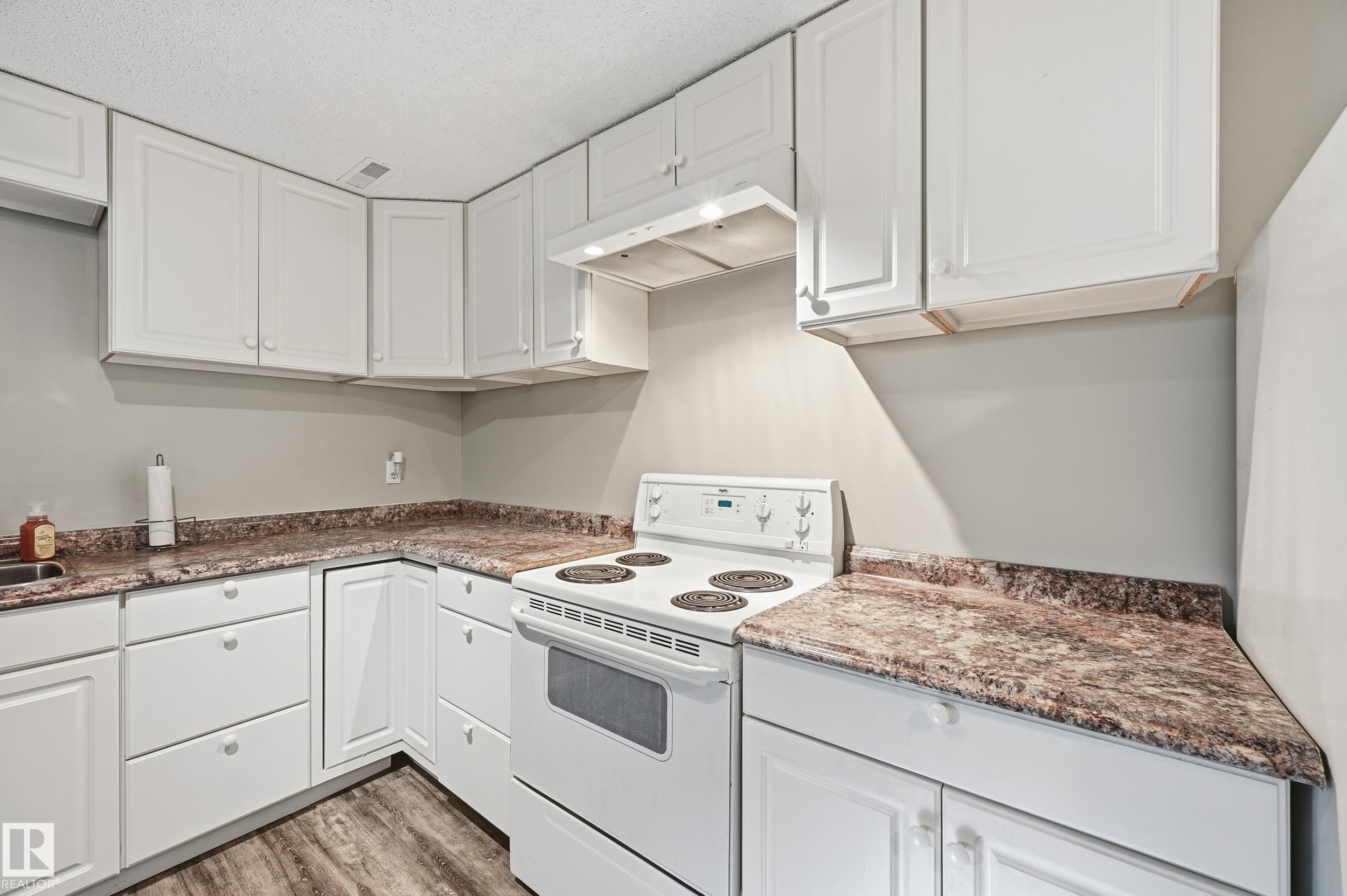 Kitchen with electric range, white cabinets, light wood-type flooring, and a textured ceiling - 2952 39 Avenue, Edmonton, AB - Indoor Photo Showing Kitchen