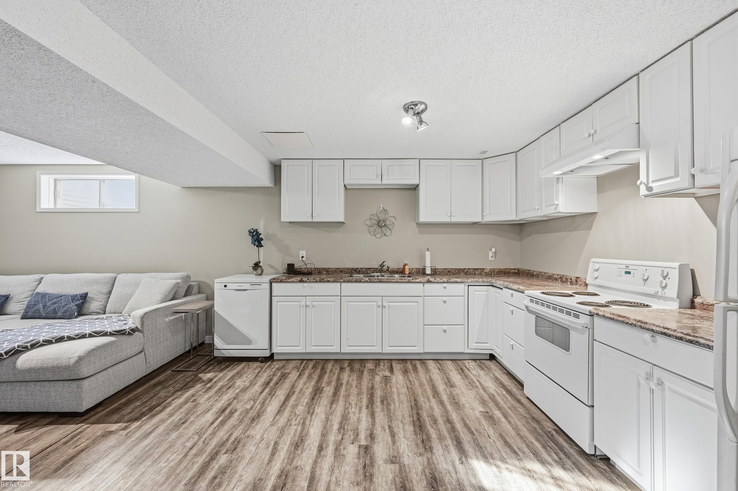 Kitchen featuring white appliances, white cabinets, light wood finished floors, and a textured ceiling - 2952 39 Avenue, Edmonton, AB - Indoor Photo Showing Kitchen