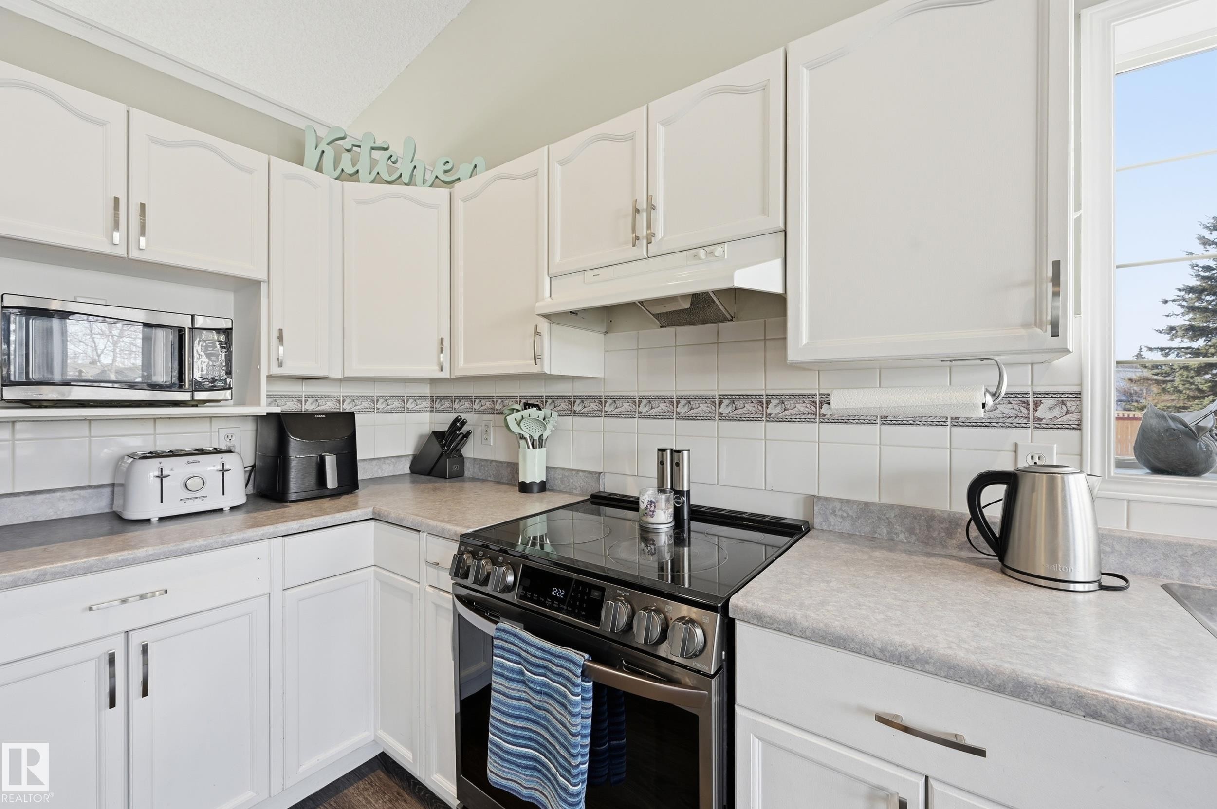 Kitchen featuring stainless steel appliances, white cabinetry, and light countertops - 2952 39 Avenue, Edmonton, AB - Indoor Photo Showing Kitchen