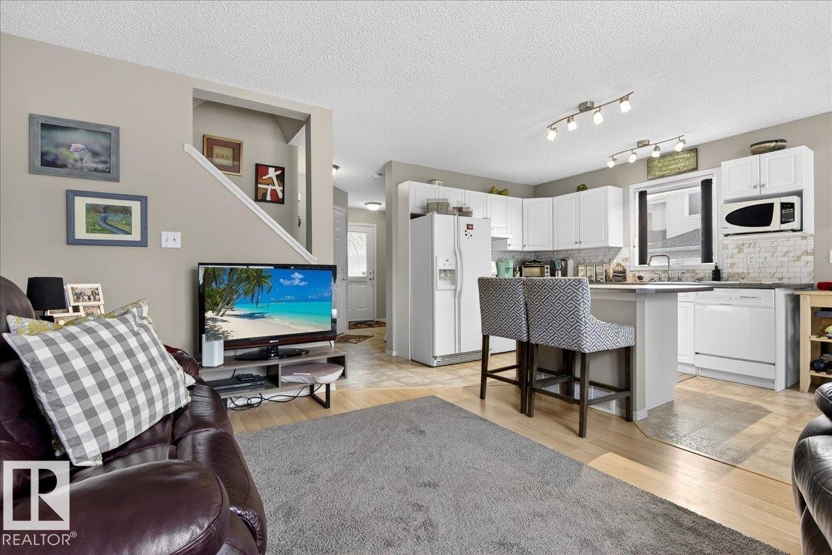 Living area featuring light wood-type flooring and a textured ceiling - 23 4020 21 Street, Edmonton, AB - Indoor