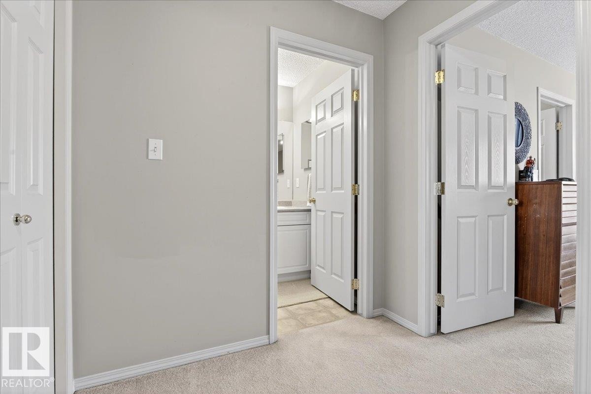 Hall with a textured ceiling and light colored carpet - 23 4020 21 Street, Edmonton, AB - Indoor Photo Showing Other Room