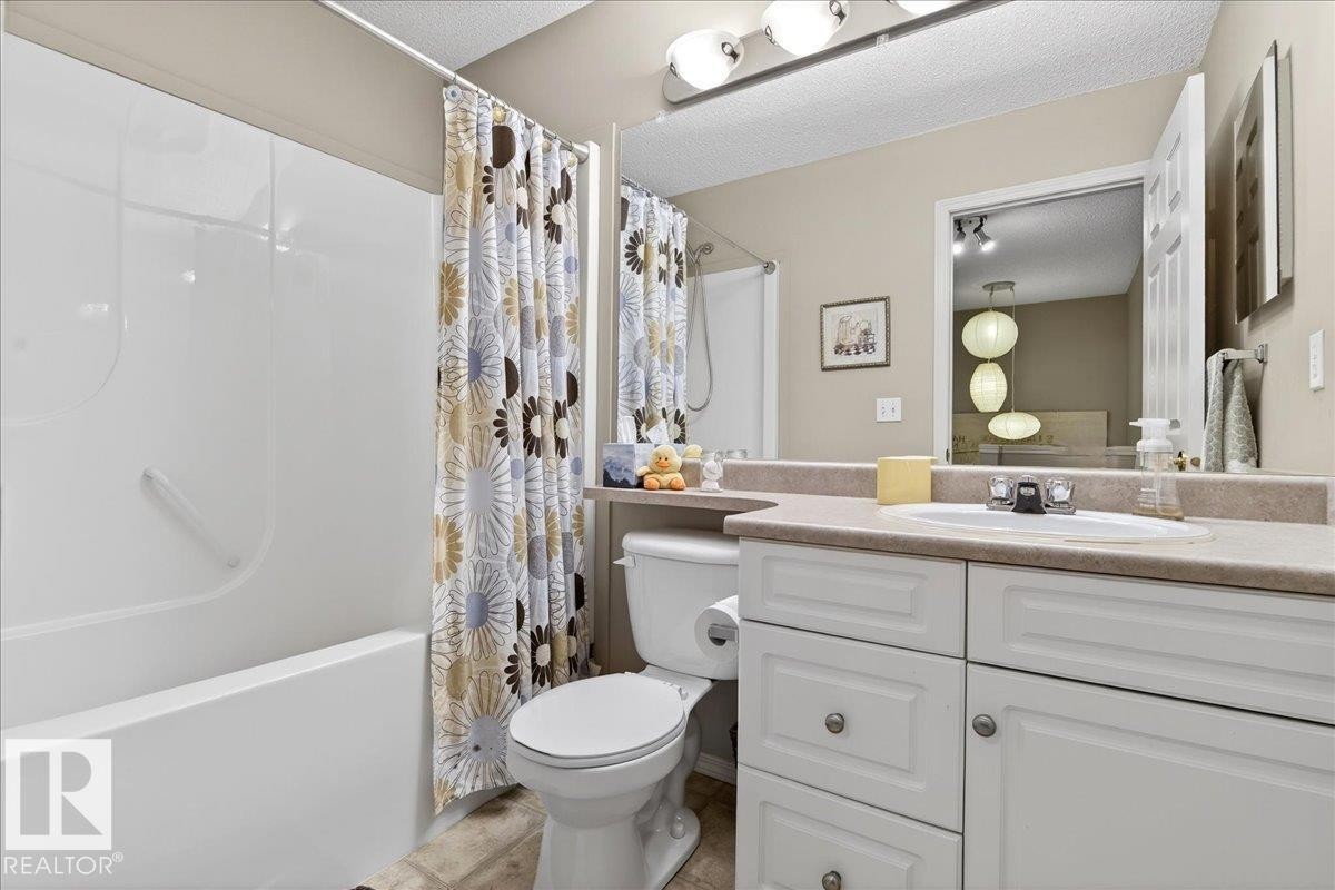 Bathroom with vanity, shower / bath combination with curtain, and a textured ceiling - 23 4020 21 Street, Edmonton, AB - Indoor Photo Showing Bathroom
