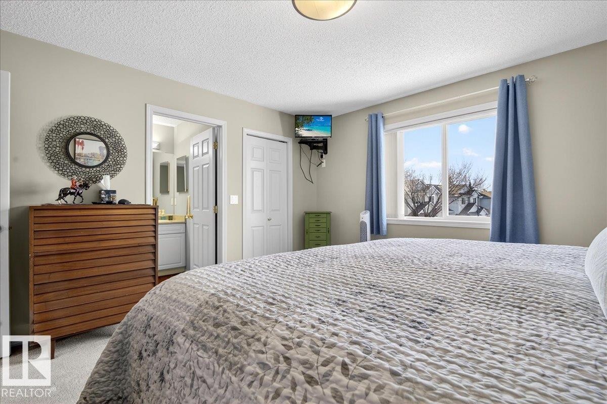 Carpeted bedroom featuring a textured ceiling, a closet, and connected bathroom - 23 4020 21 Street, Edmonton, AB - Indoor Photo Showing Bedroom