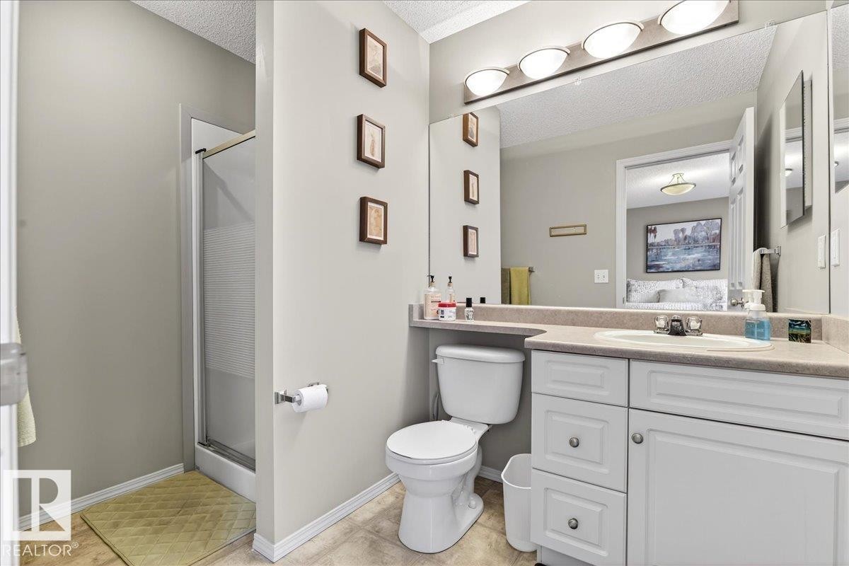 Full bath with a stall shower, a textured ceiling, vanity, and ensuite bath - 23 4020 21 Street, Edmonton, AB - Indoor Photo Showing Bathroom
