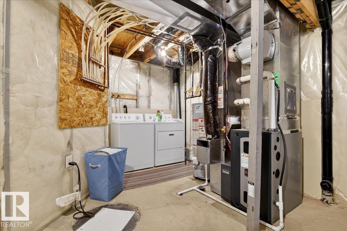 Unfinished below grade area featuring washing machine and dryer, heating unit, and gas water heater - 23 4020 21 Street, Edmonton, AB - Indoor Photo Showing Laundry Room