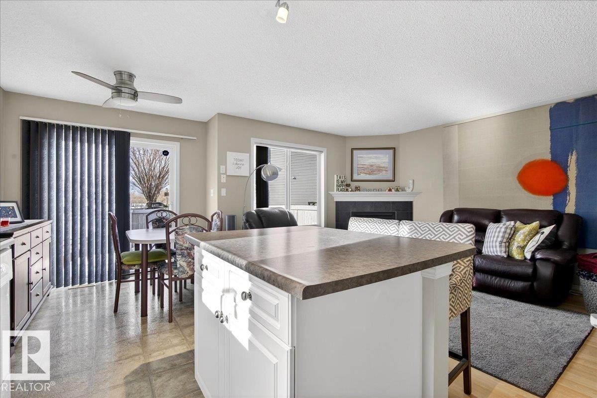 Kitchen with dark countertops, open floor plan, a breakfast bar area, white cabinetry, and a textured ceiling - 23 4020 21 Street, Edmonton, AB - Indoor