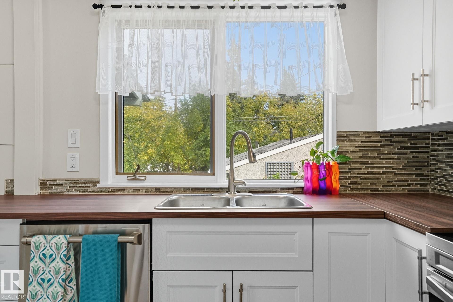 Kitchen with white cabinetry, appliances with stainless steel finishes, butcher block countertops, and tasteful backsplash - 11222 71 Avenue, Edmonton, AB - Indoor Photo Showing Kitchen With Double Sink