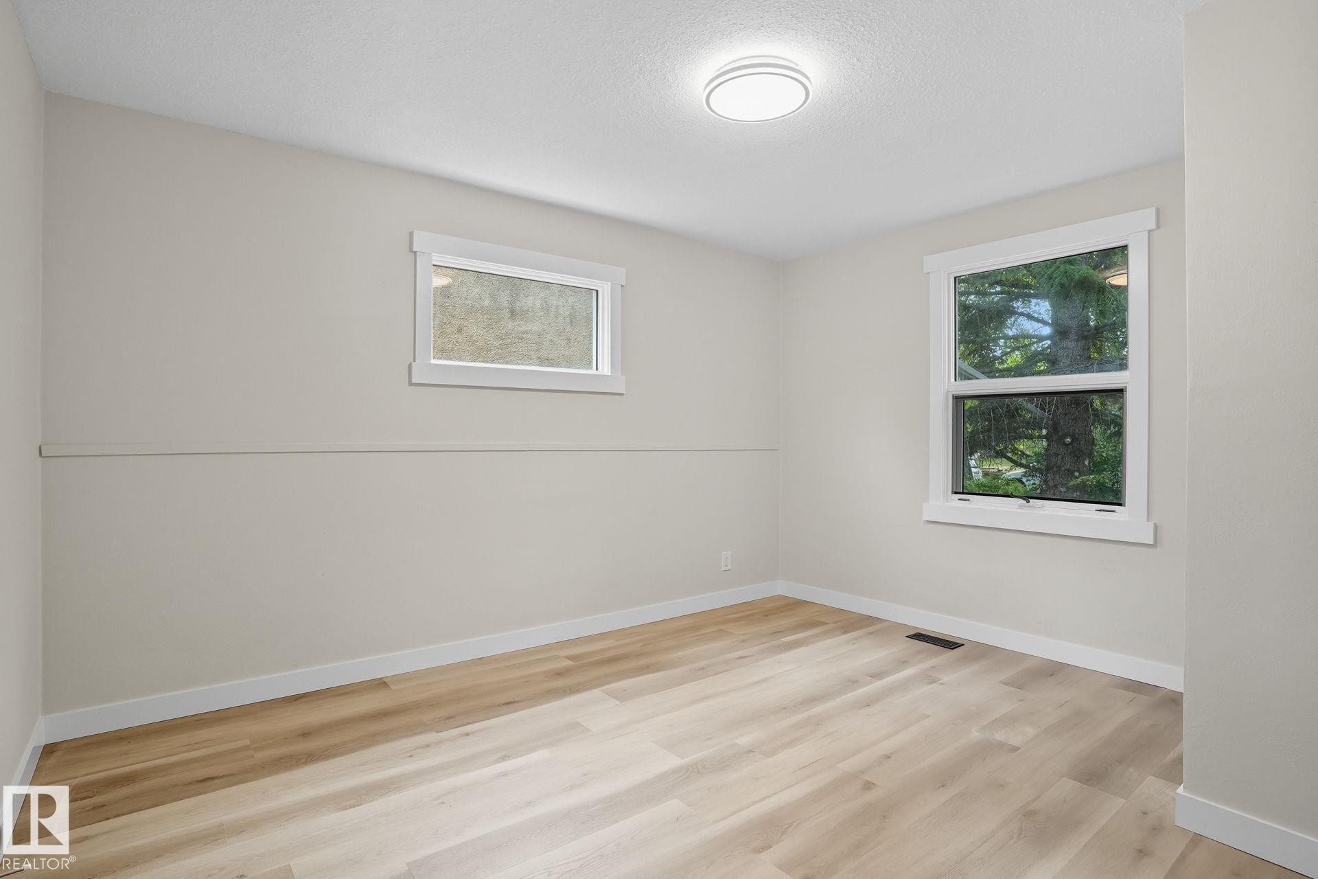 Unfurnished room featuring plenty of natural light, light wood-style flooring, and a textured ceiling - 11222 71 Avenue, Edmonton, AB - Indoor Photo Showing Other Room