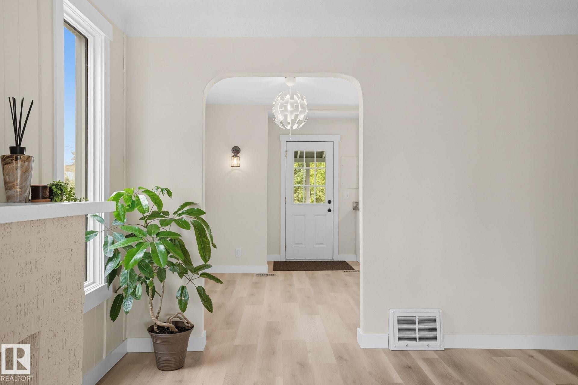 Entryway with light wood-style flooring, a chandelier, and arched walkways - 11222 71 Avenue, Edmonton, AB - Indoor Photo Showing Other Room