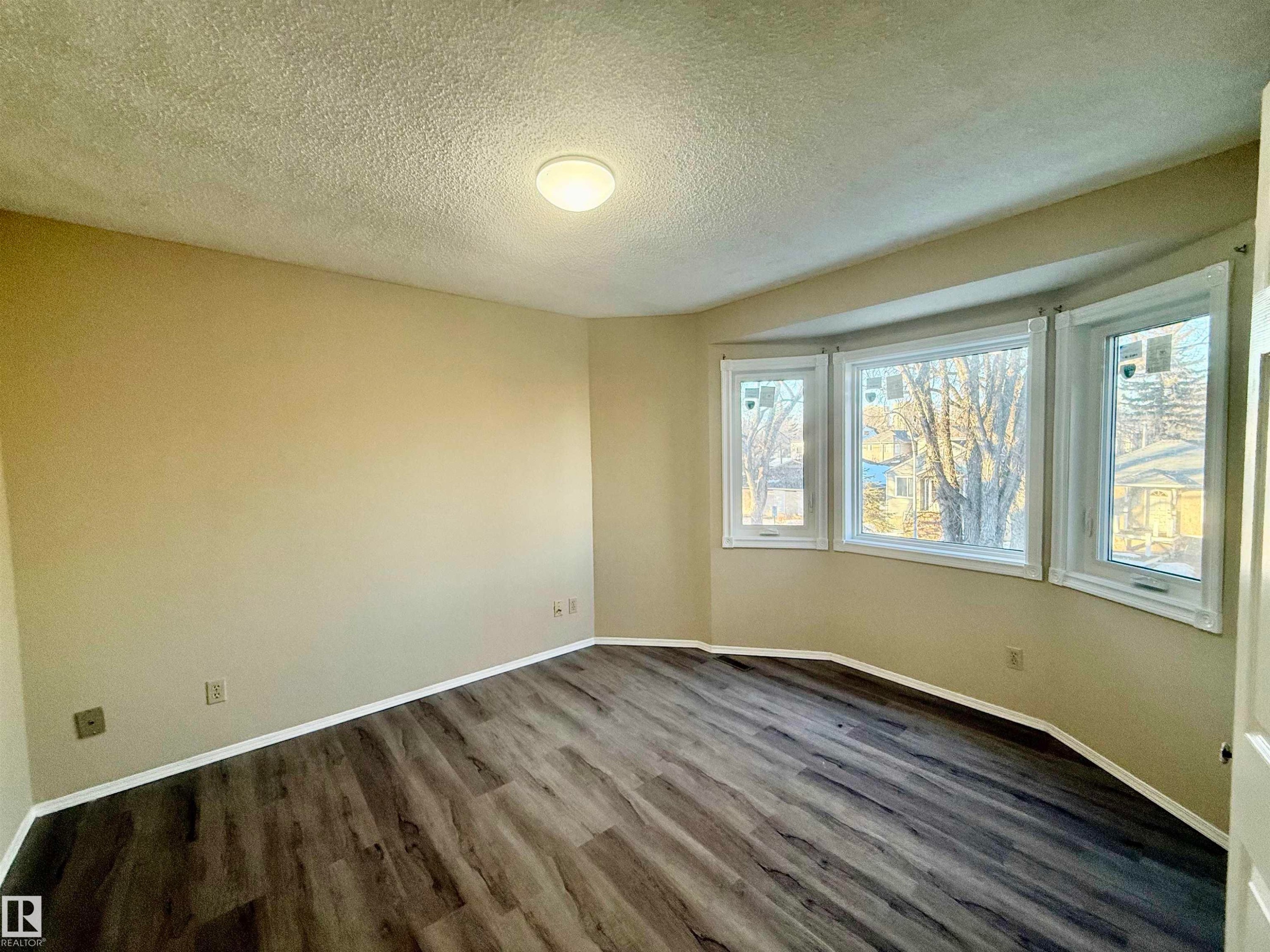 Empty room with a textured ceiling and dark wood finished floors - 10905 74 Avenue, Edmonton, AB - Indoor Photo Showing Other Room