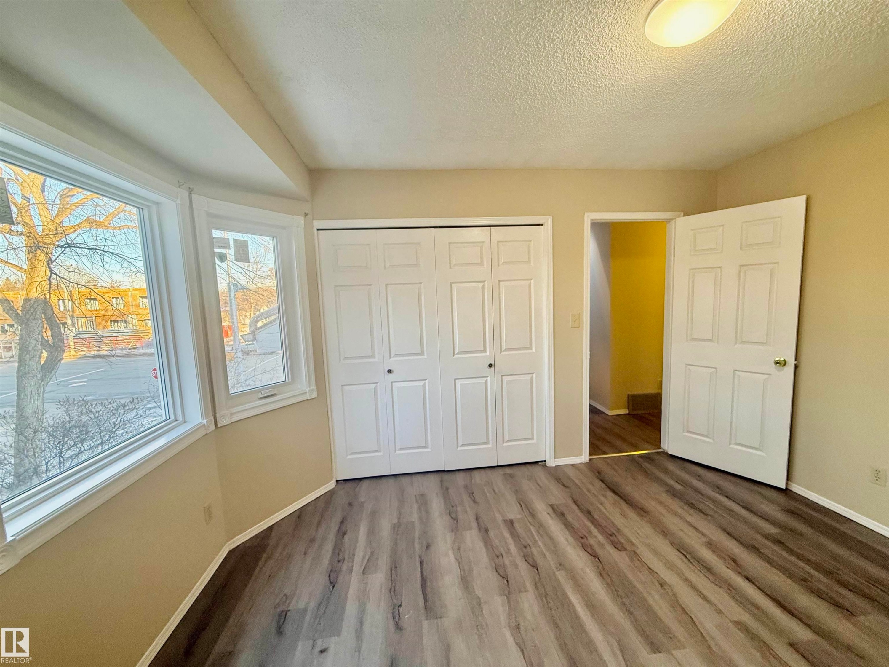 Unfurnished bedroom with a closet, wood finished floors, and a textured ceiling - 10905 74 Avenue, Edmonton, AB - Indoor Photo Showing Other Room