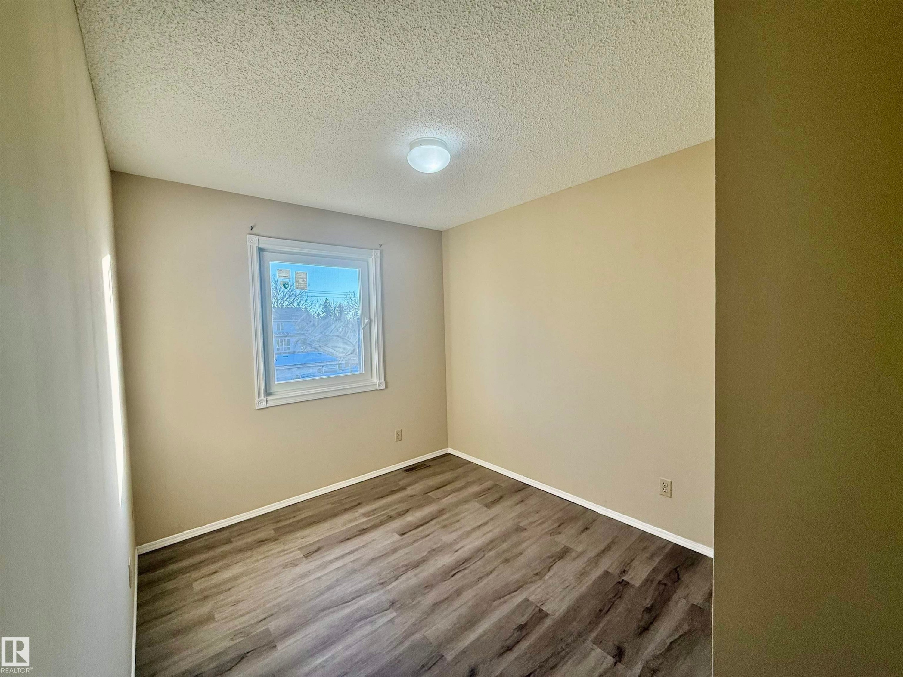 Spare room featuring a textured ceiling and wood finished floors - 10905 74 Avenue, Edmonton, AB - Indoor Photo Showing Other Room