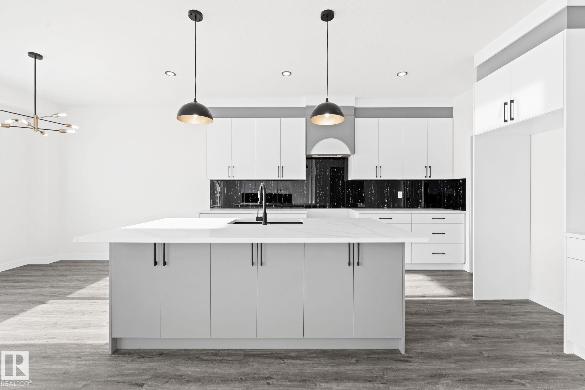 Kitchen featuring backsplash, white cabinetry, dark wood-style floors, an island with sink, and suspended lighting - 3 Pierwyck Loop, Spruce Grove, AB - Indoor Photo Showing Kitchen With Upgraded Kitchen