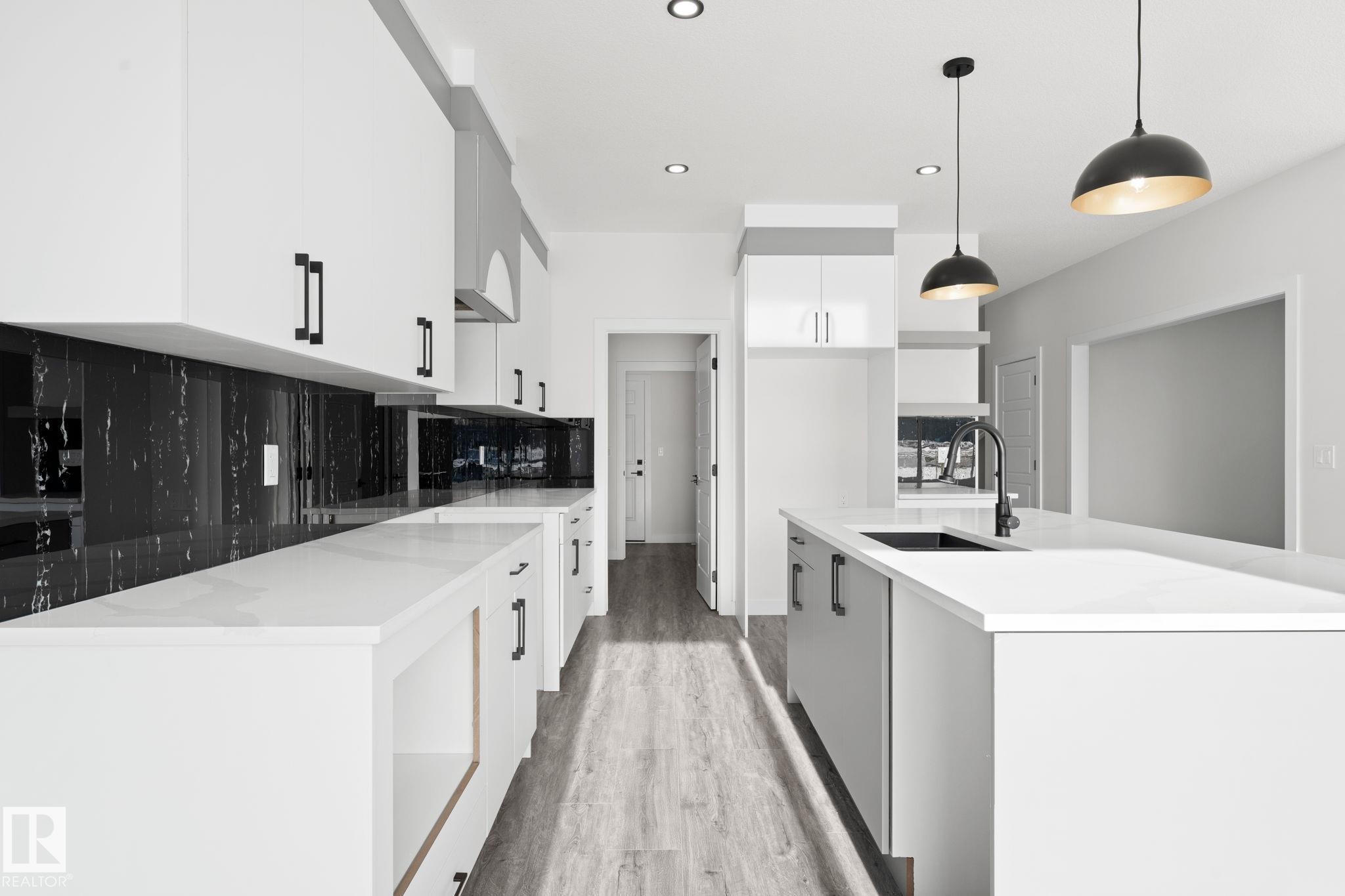 Dual tone kitchen featuring modern cabinets, tasteful backsplash, a kitchen island with sink, light stone counters, and two tone cabinets - 3 Pierwyck Loop, Spruce Grove, AB - Indoor Photo Showing Kitchen With Upgraded Kitchen