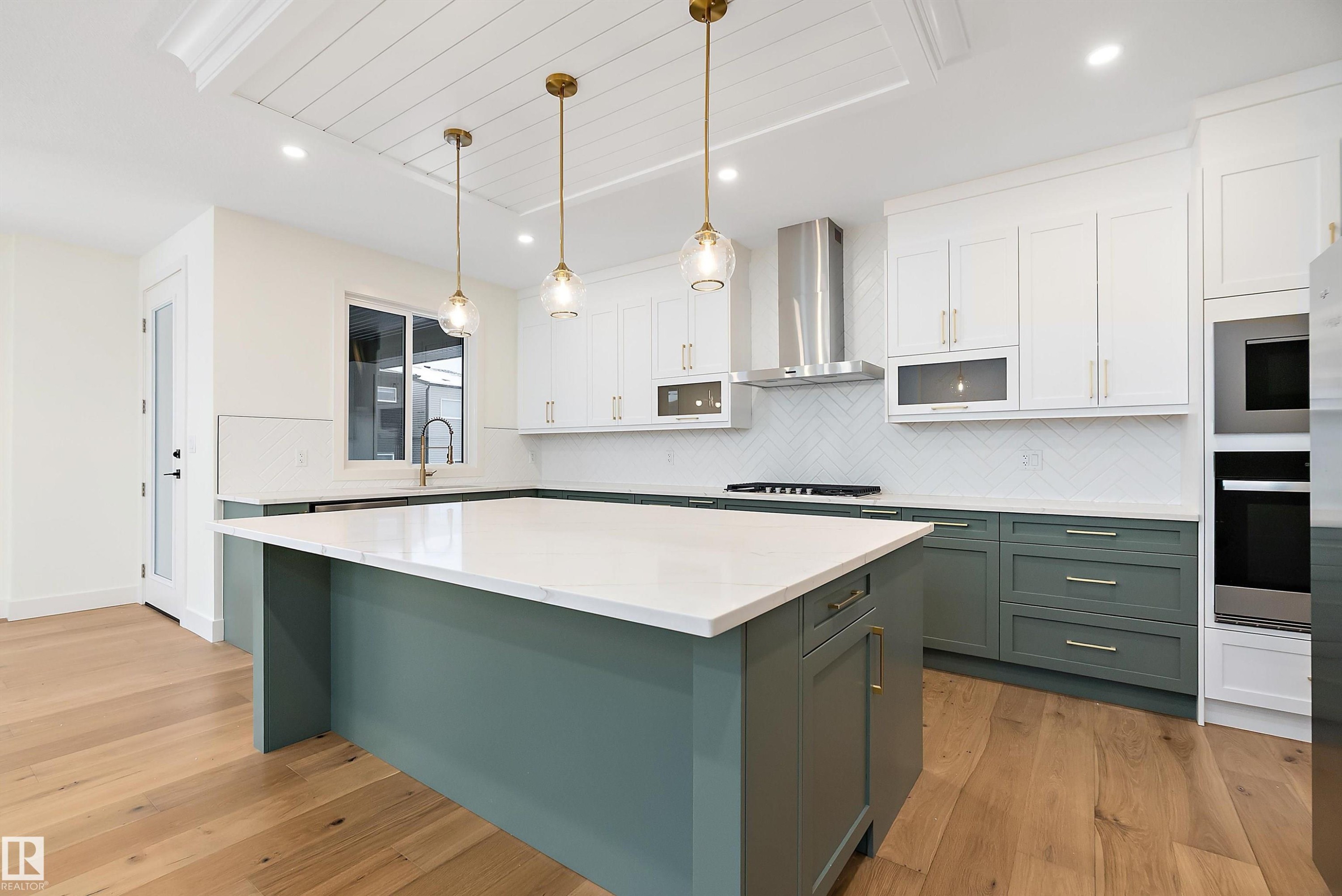 Two tone kitchen featuring two tone cabinets, light wood-style flooring, wall oven, tasteful backsplash, and decorative light fixtures - Edmonton, AB - Indoor Photo Showing Kitchen With Upgraded Kitchen