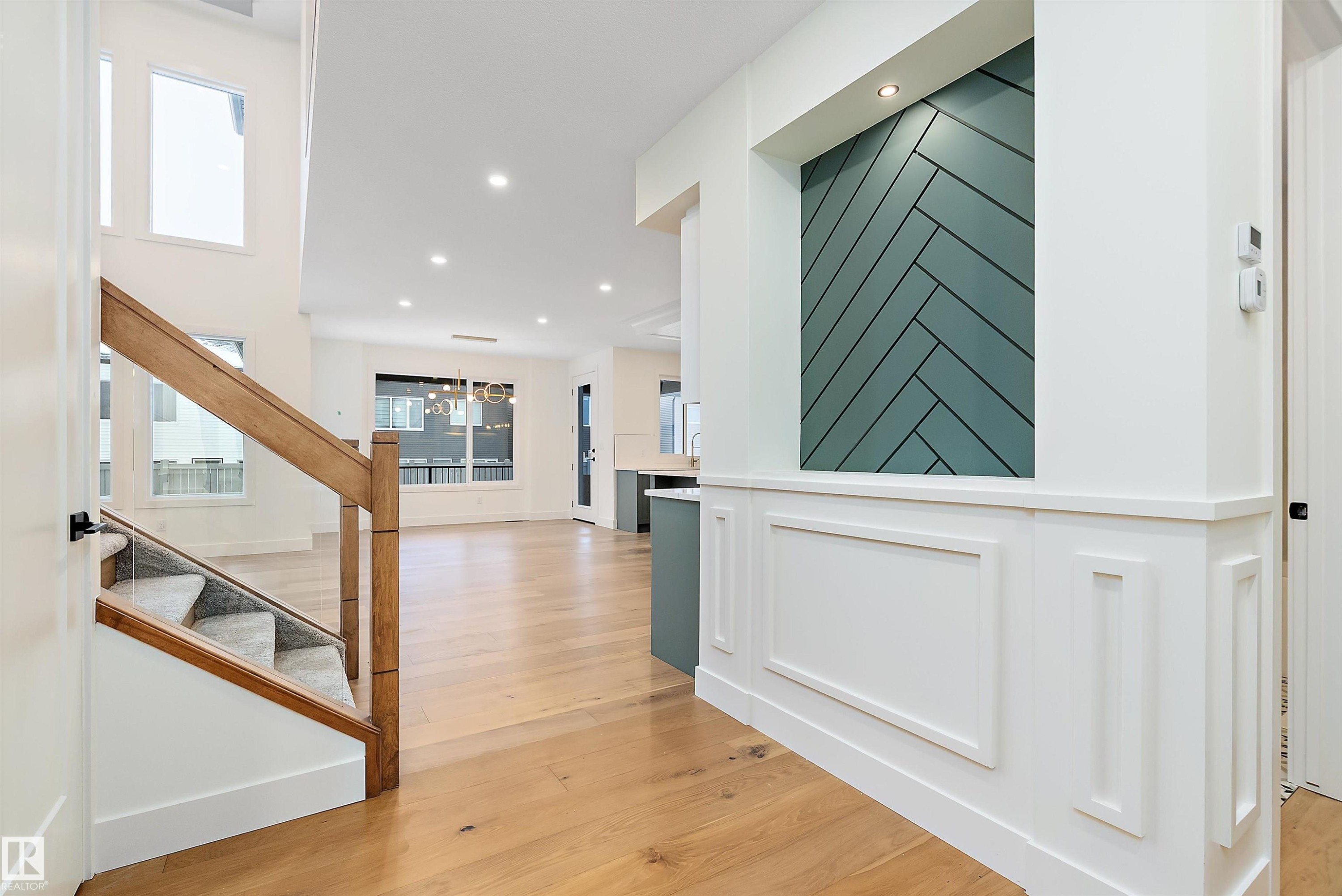 Stairs with hardwood / wood-style flooring and suspended lighting - Edmonton, AB - Indoor Photo Showing Other Room