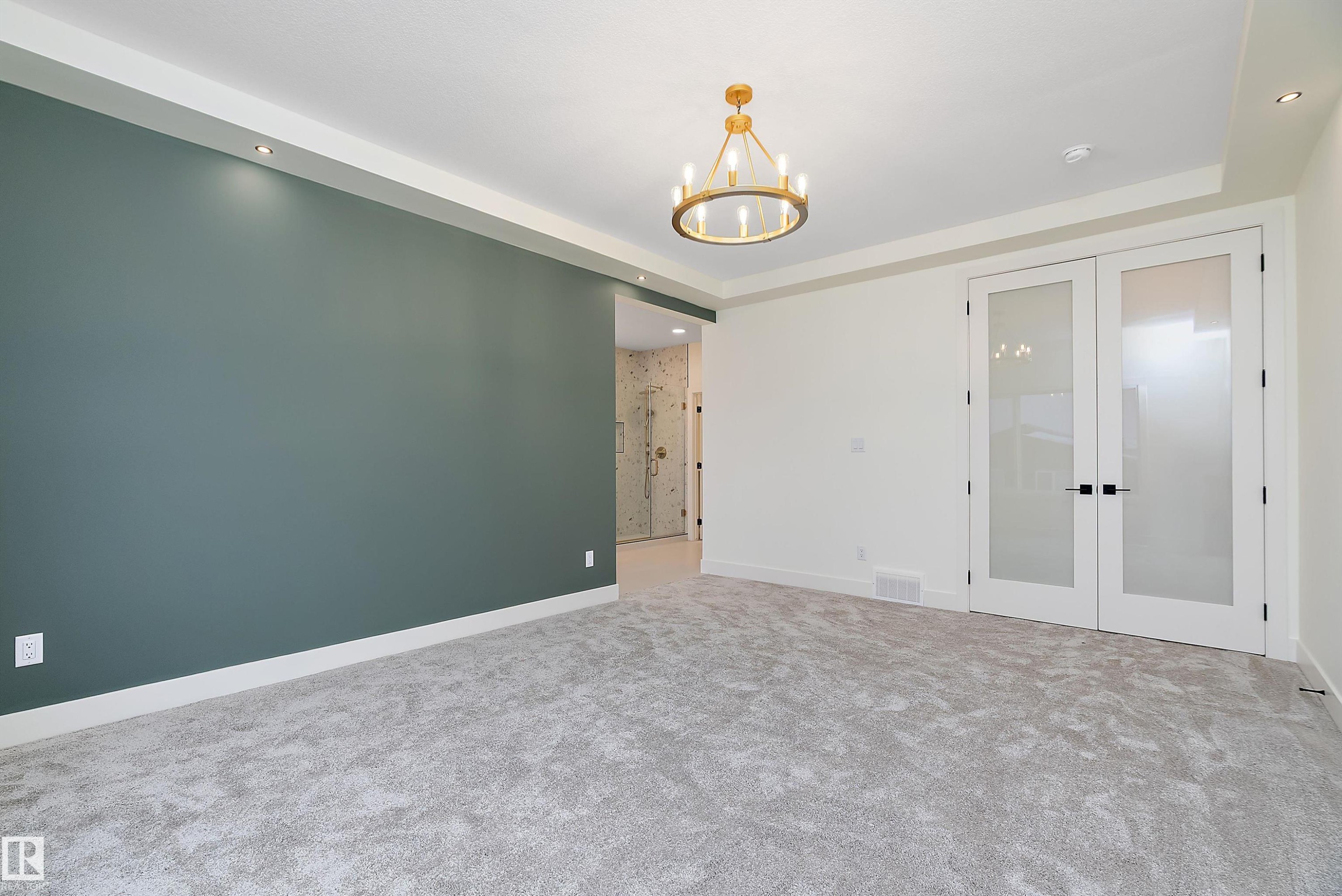 Carpeted spare room with french doors, suspended lighting, and a raised ceiling - Edmonton, AB - Indoor Photo Showing Other Room