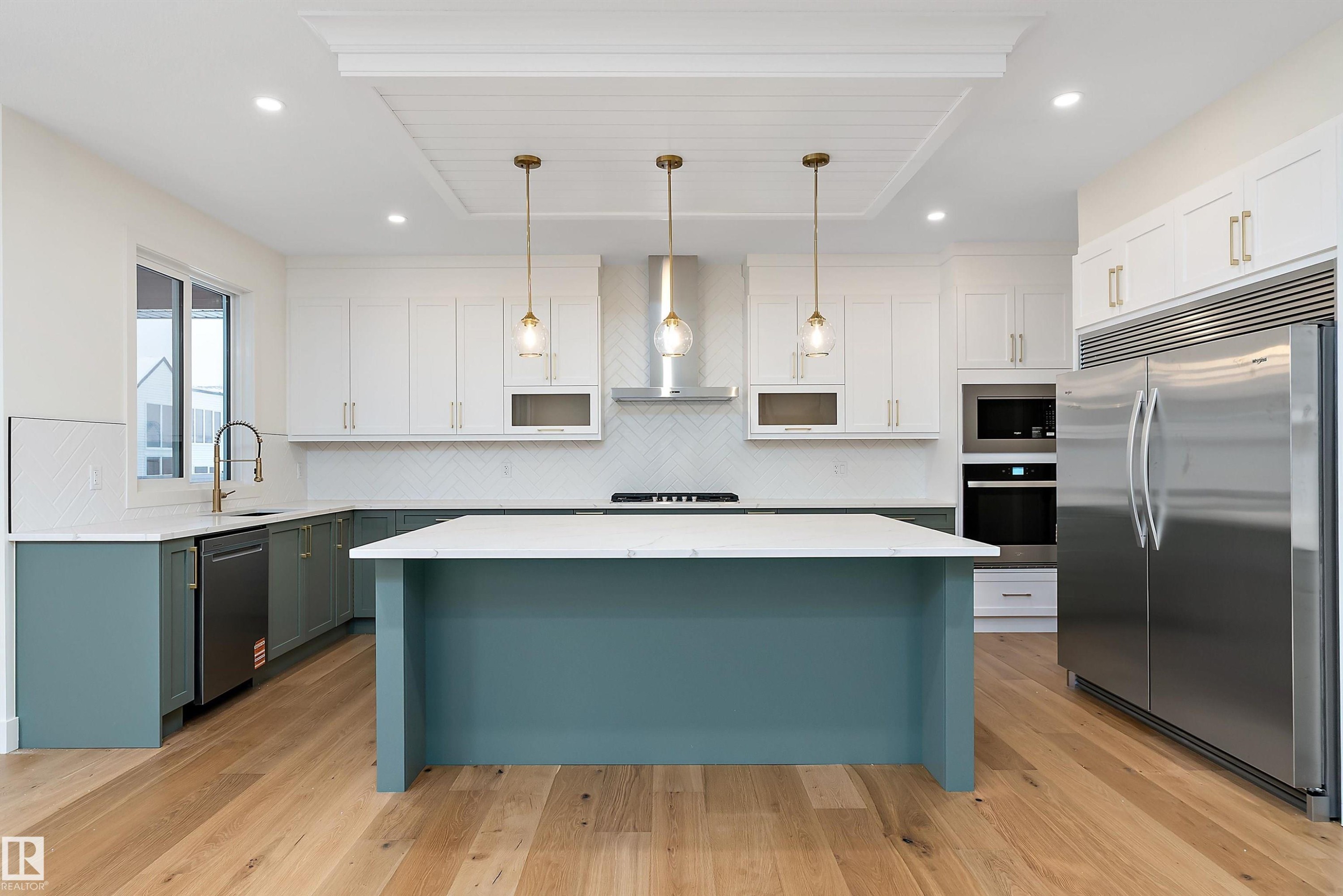 Dual tone kitchen featuring built in appliances, hanging light fixtures, light wood-style floors, two tone cabinetry, and tasteful backsplash - Edmonton, AB - Indoor Photo Showing Kitchen With Upgraded Kitchen