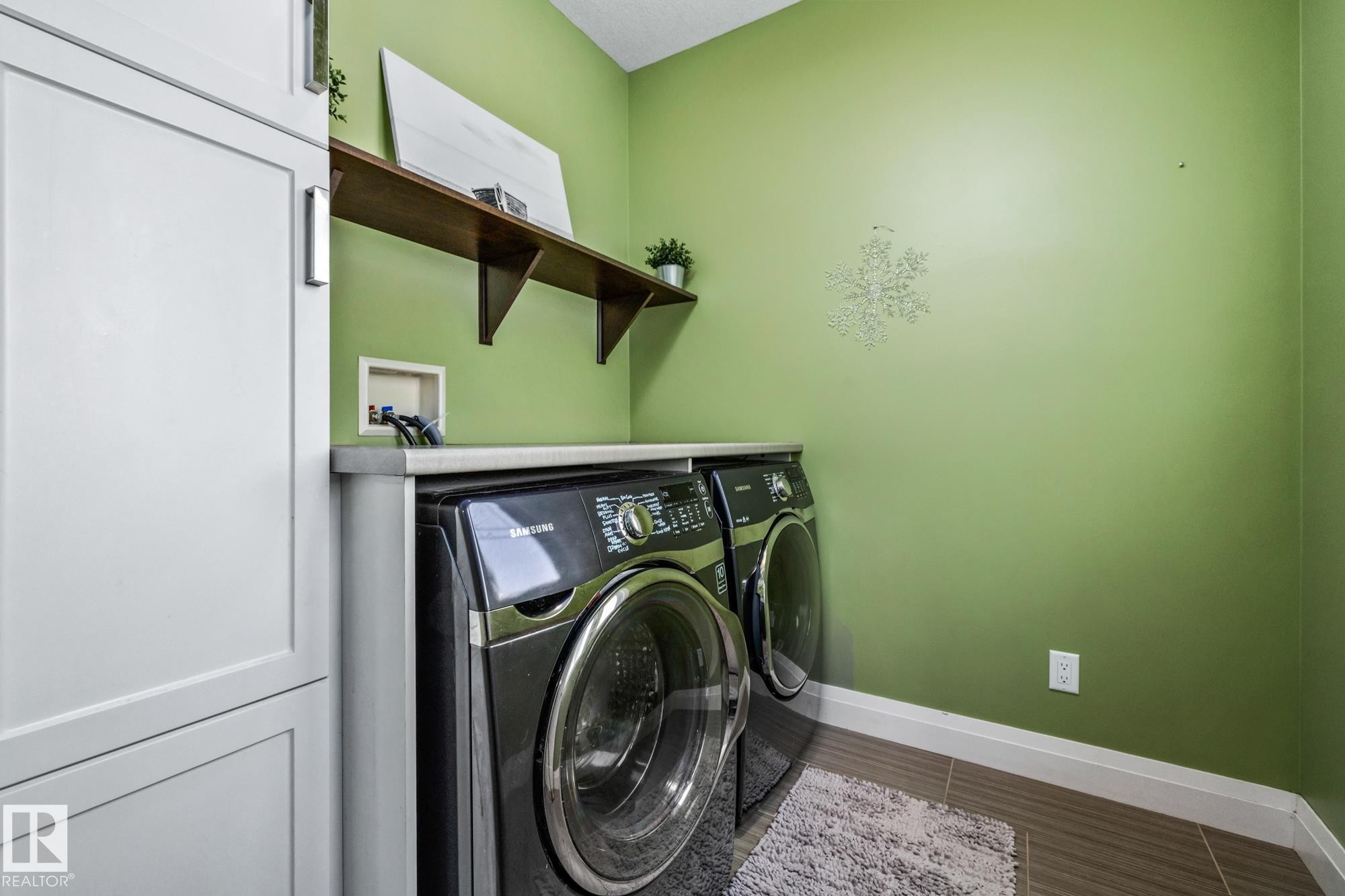 Laundry area with cabinet space, washer and dryer, and wood finish floors - 14 Spring Bay, Spruce Grove, AB - Indoor Photo Showing Laundry Room