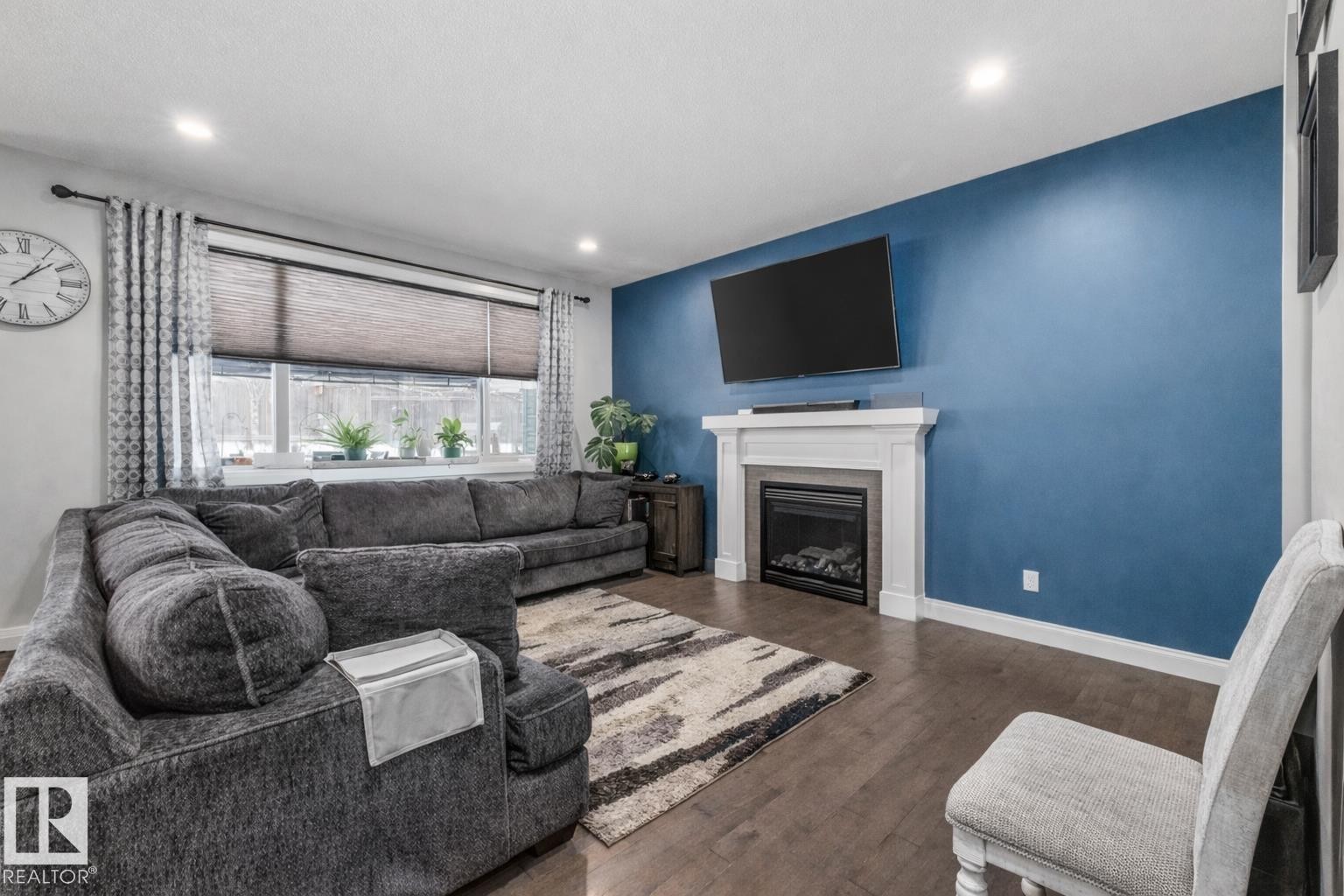Living room featuring dark wood finished floors and a fireplace - 14 Spring Bay, Spruce Grove, AB - Indoor Photo Showing Living Room With Fireplace