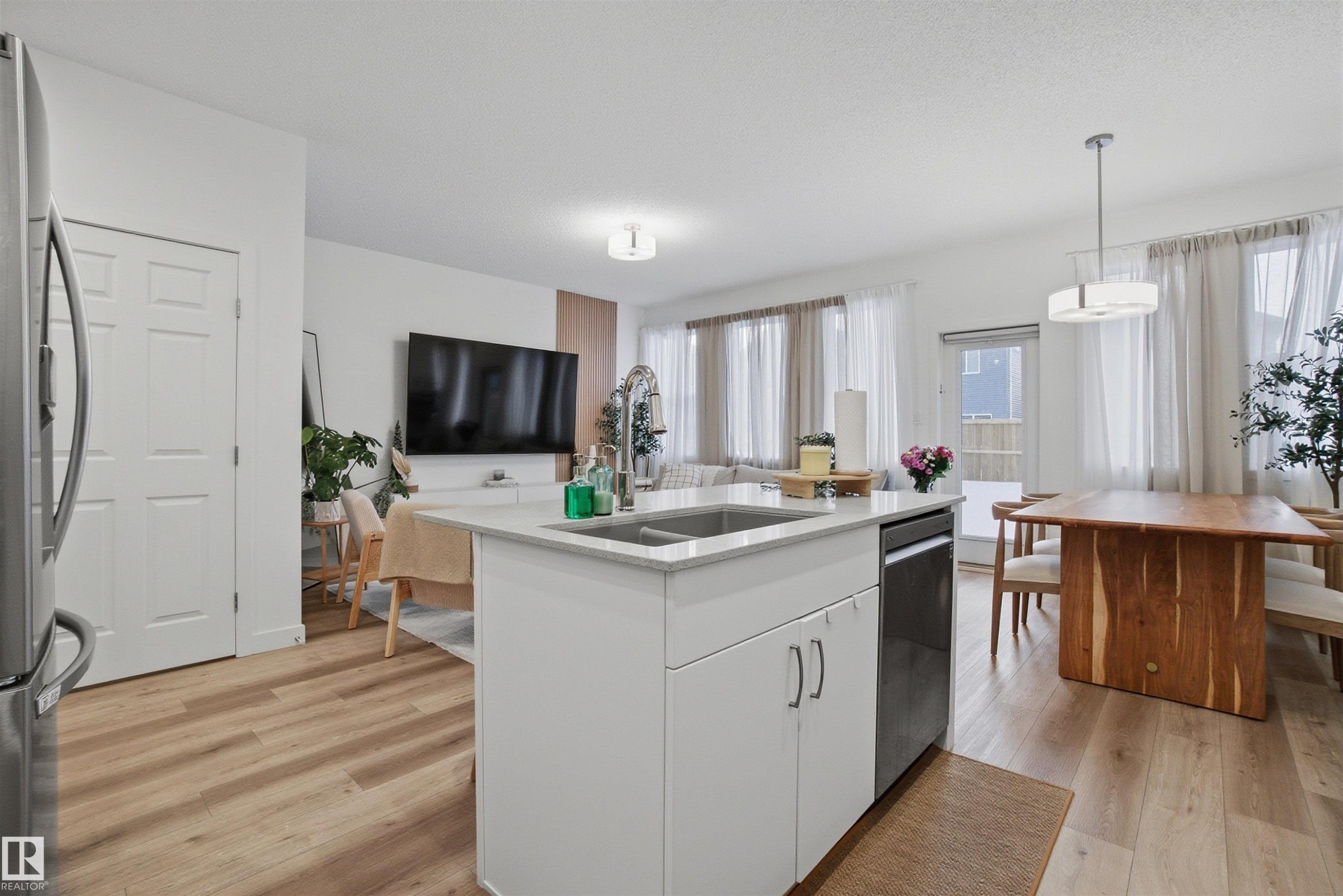 Kitchen featuring white cabinets, open floor plan, stainless steel appliances, a kitchen island with sink, and light wood-style floors - 9882 225A St Nw, Edmonton, AB - Indoor Photo Showing Kitchen With Double Sink