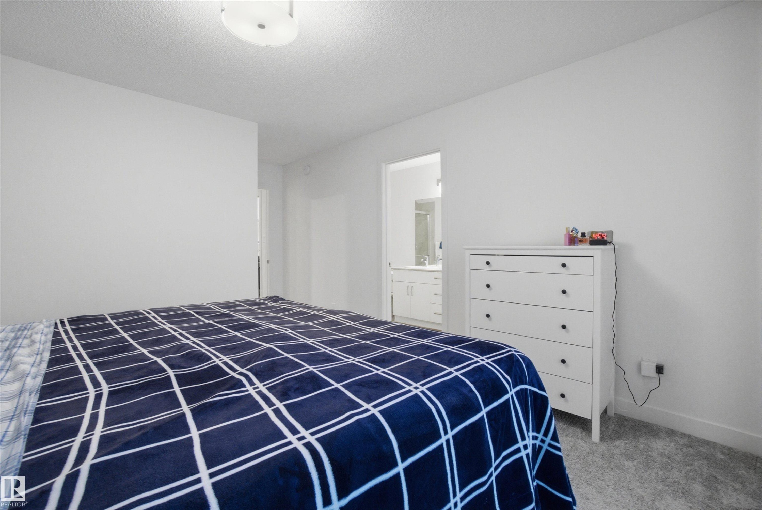 Carpeted bedroom featuring ensuite bath and a textured ceiling - 9882 225A St Nw, Edmonton, AB - Indoor Photo Showing Bedroom