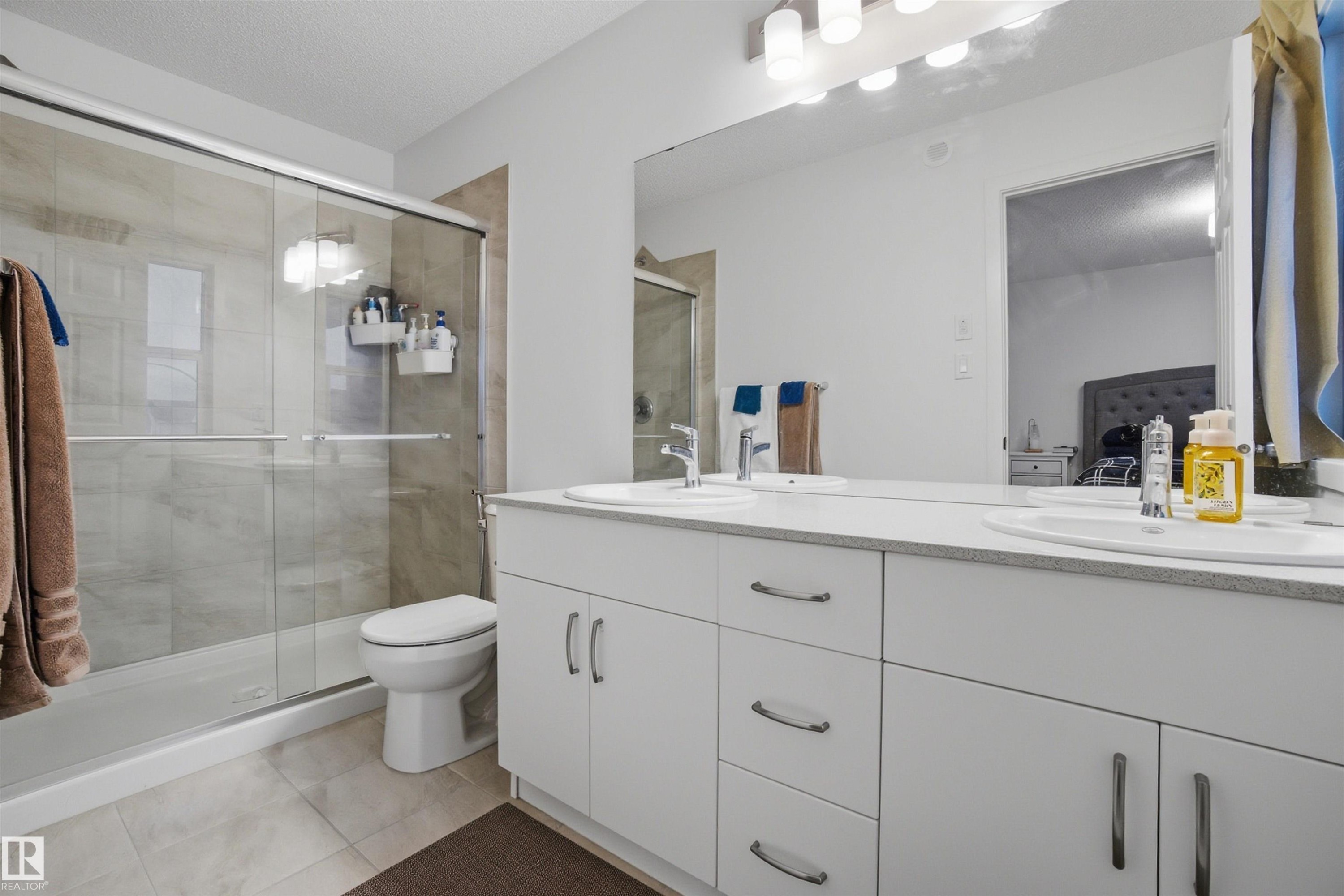 Bathroom featuring double vanity, a shower stall, light tile patterned flooring, and a textured ceiling - 9882 225A St Nw, Edmonton, AB - Indoor Photo Showing Bathroom