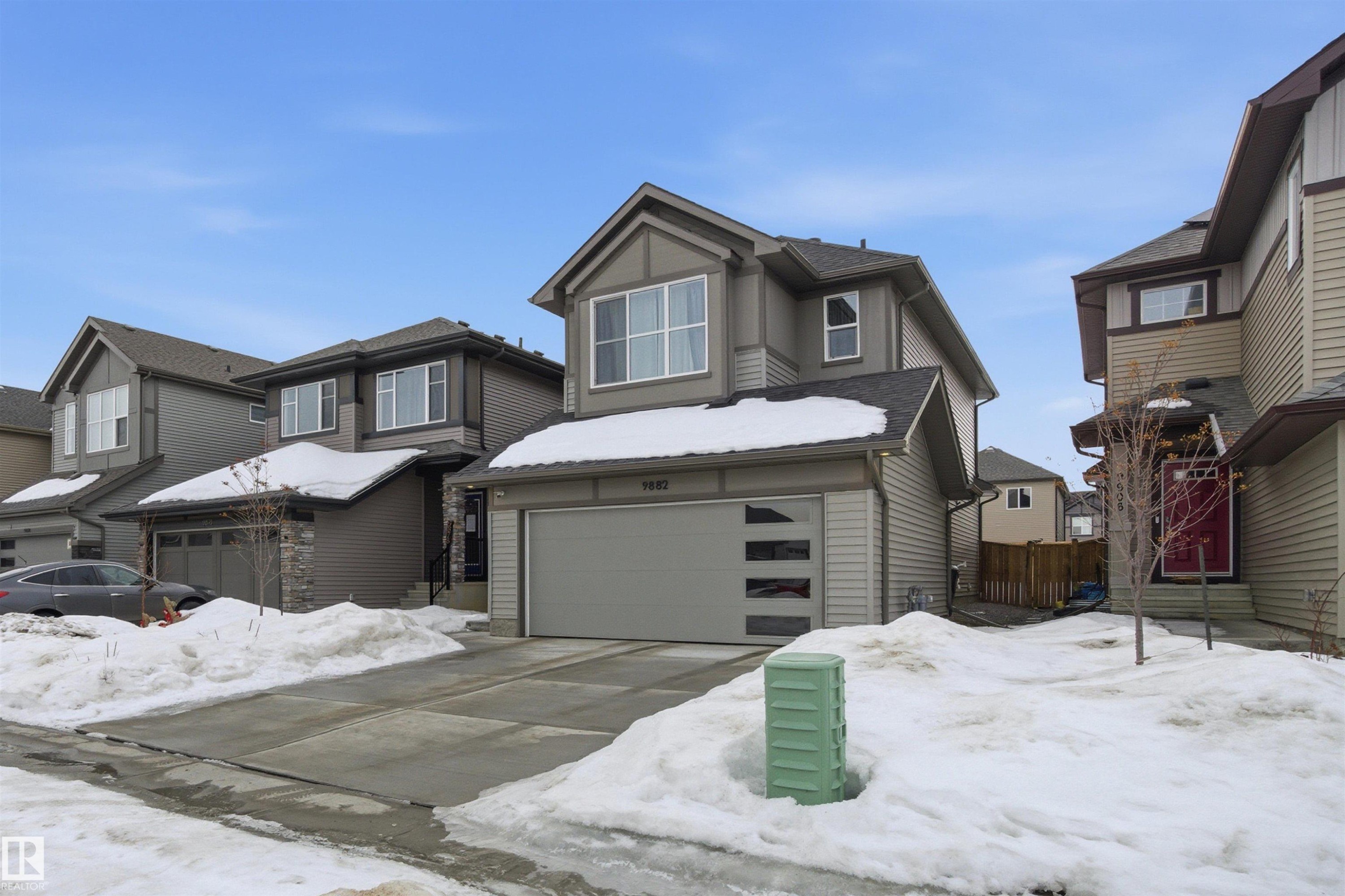 View of front of property with a garage, driveway, and a residential view - 9882 225A St Nw, Edmonton, AB - Outdoor With Facade