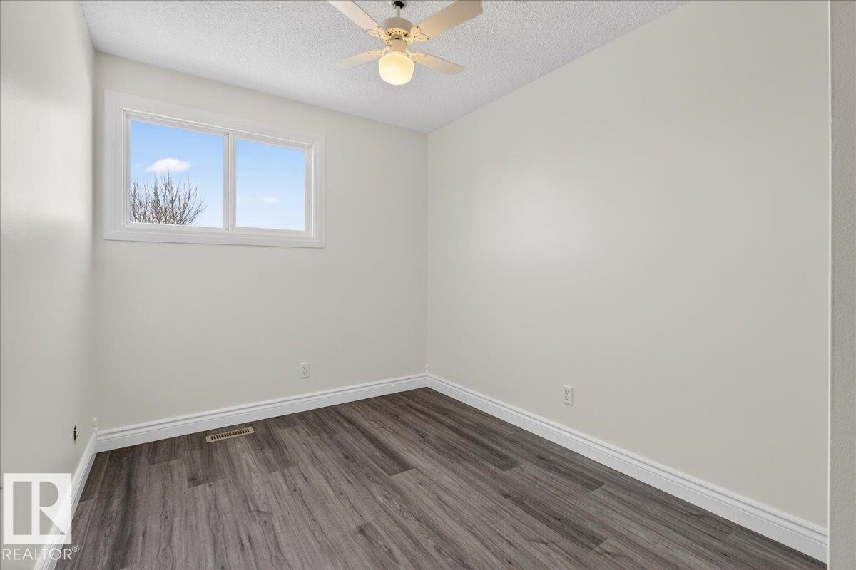 Unfurnished room featuring dark wood-type flooring, a ceiling fan, and a textured ceiling - 133 Habitat Crescent, Edmonton, AB - Indoor Photo Showing Other Room