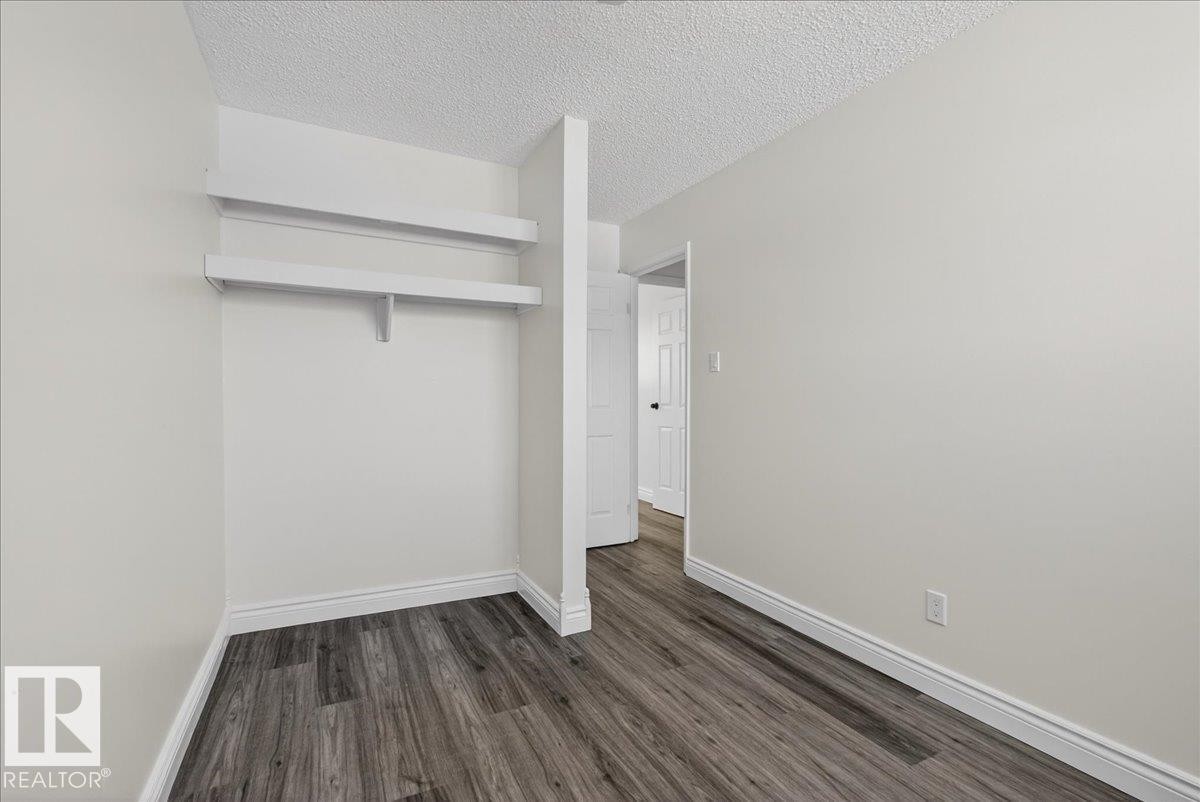 Unfurnished bedroom featuring dark wood-type flooring, a textured ceiling, and a closet - 133 Habitat Crescent, Edmonton, AB - Indoor Photo Showing Other Room