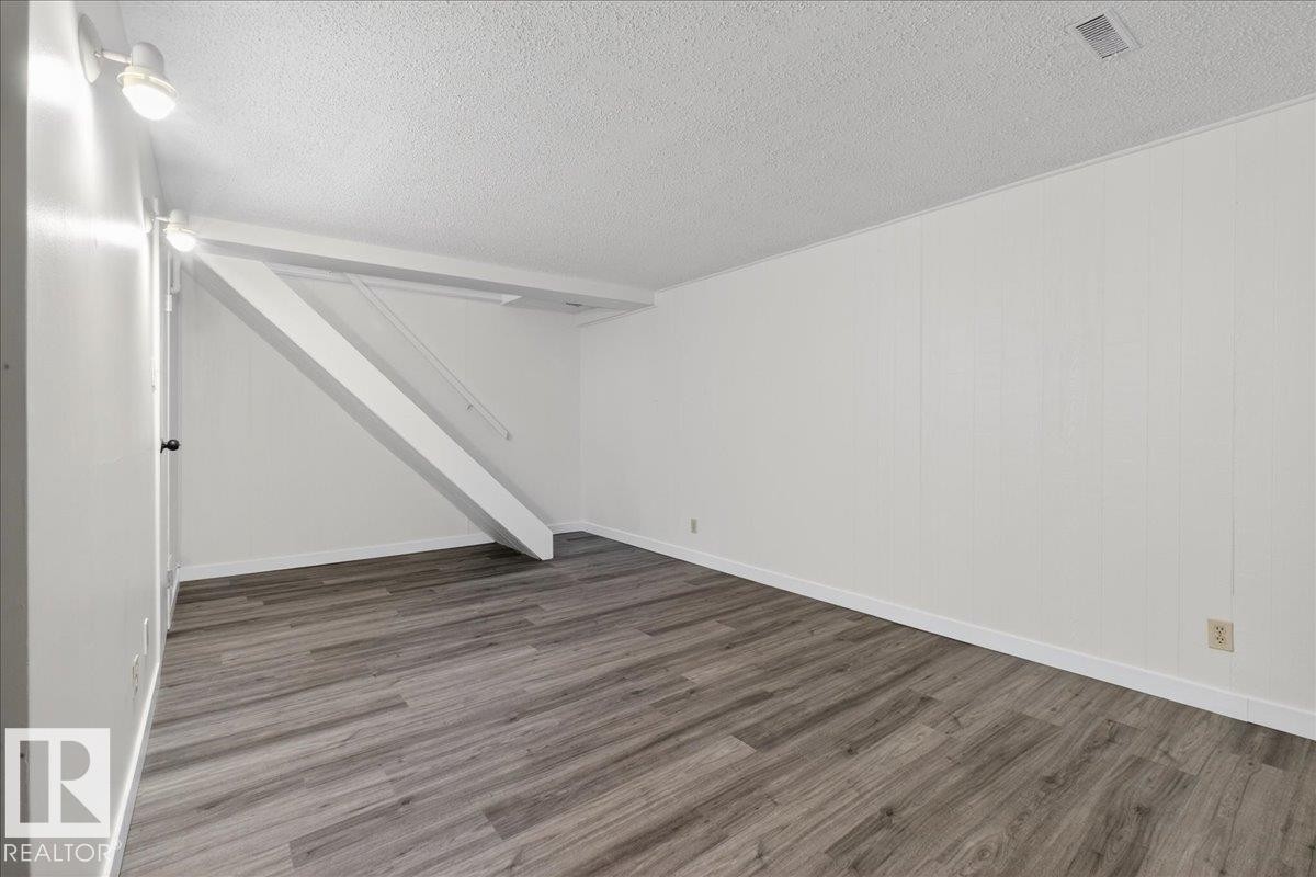 Finished below grade area with a textured ceiling and wood finished floors - 133 Habitat Crescent, Edmonton, AB - Indoor Photo Showing Other Room