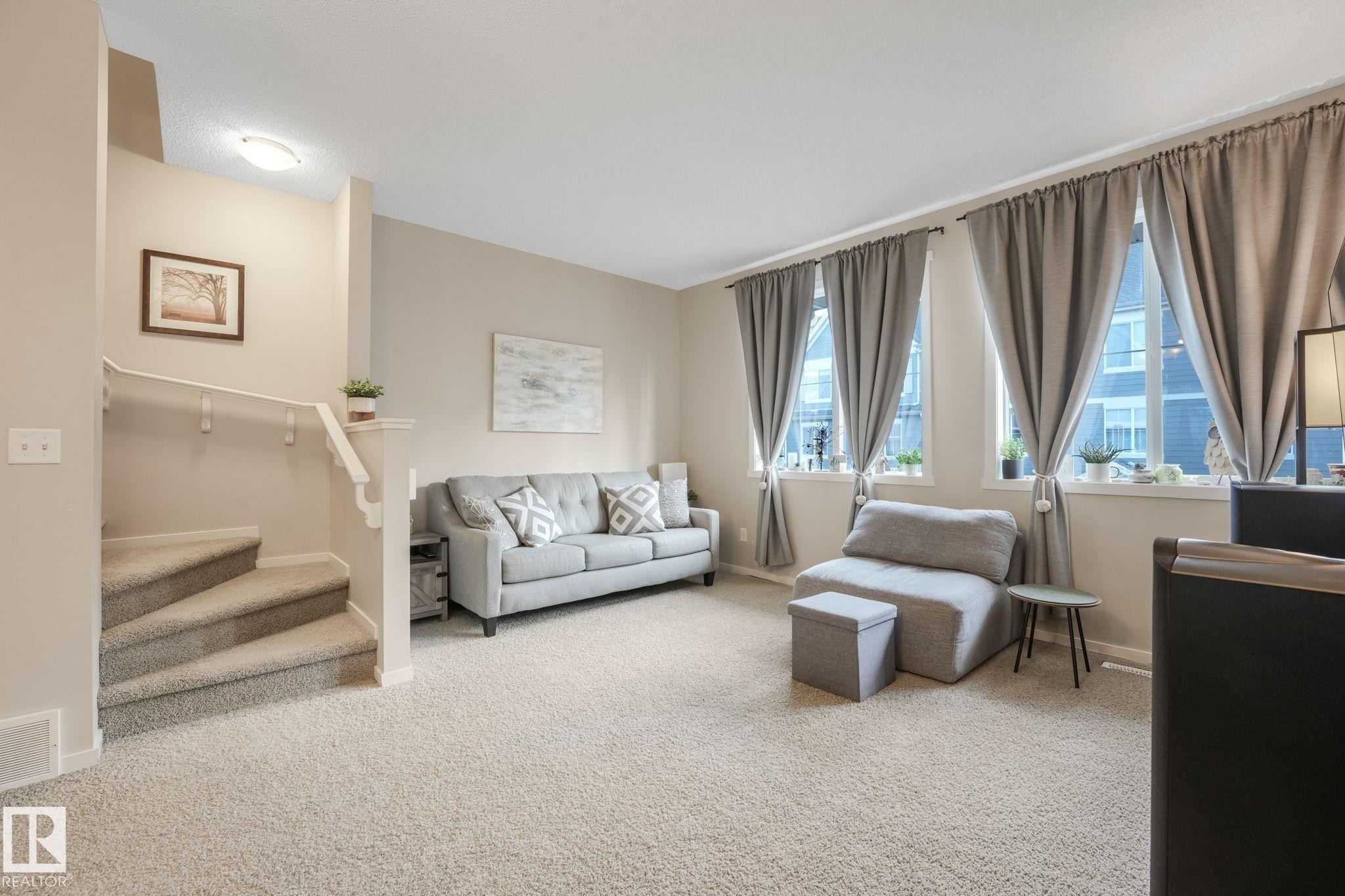 Carpeted living area featuring stairway and baseboards - 91 603 Watt Boulevard, Edmonton, AB - Indoor Photo Showing Living Room