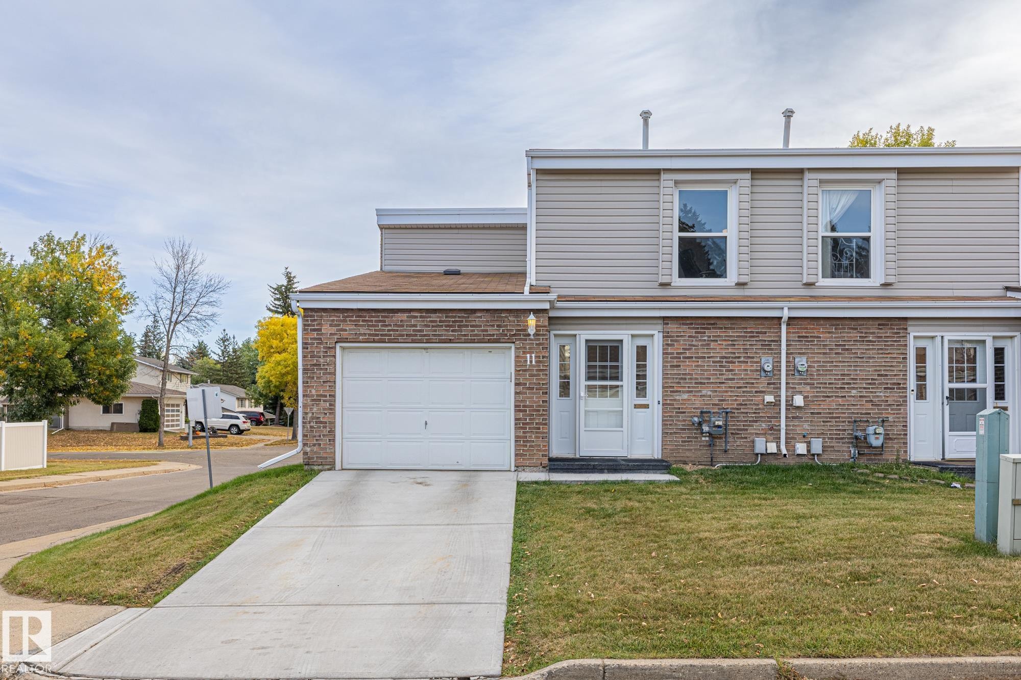 Traditional-style house featuring driveway, brick siding, a front lawn, and a garage - 11 Grandview Ridge, St. Albert, AB - Outdoor