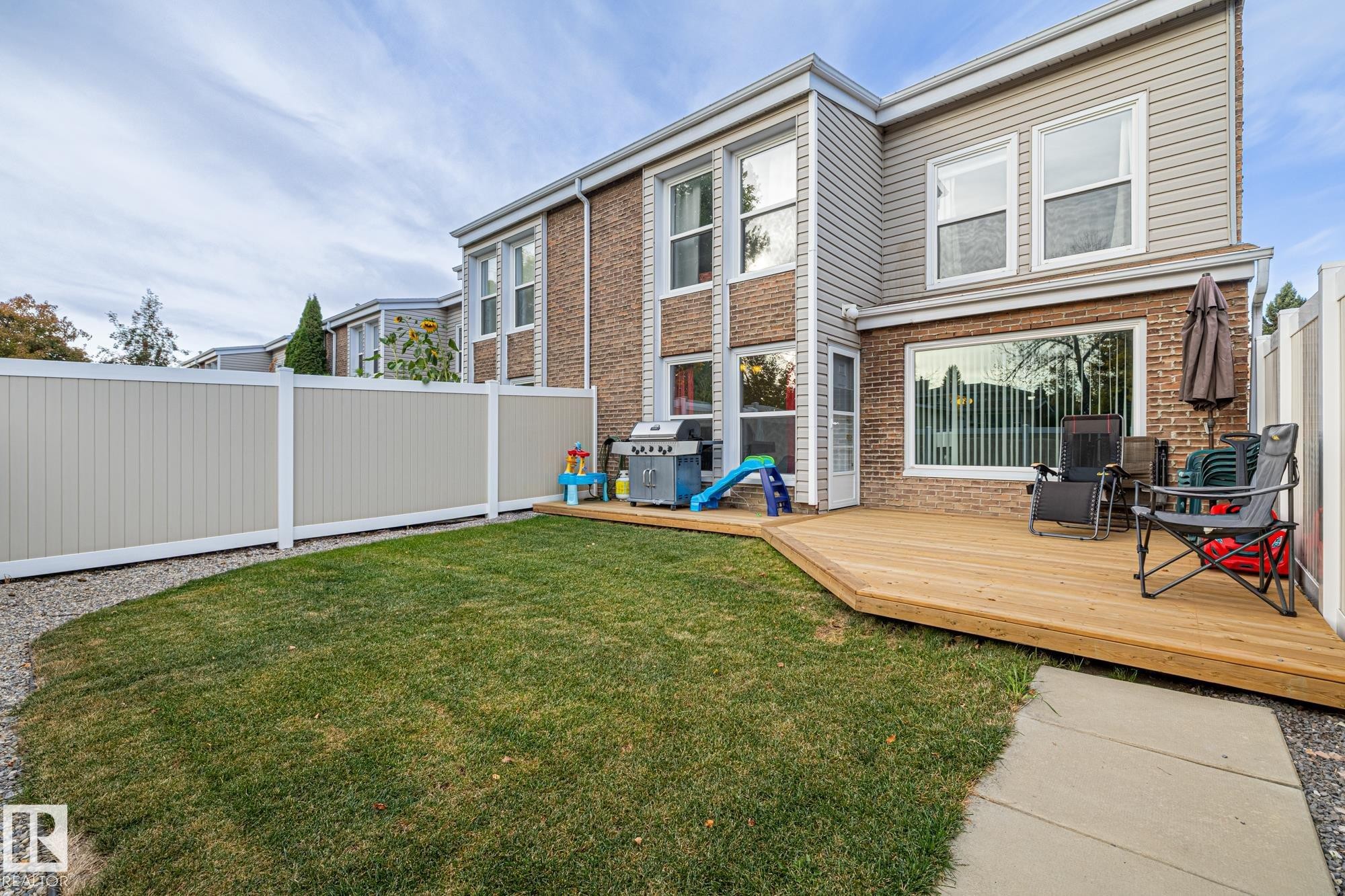 Back of house with a fenced backyard, brick siding, and a deck - 11 Grandview Ridge, St. Albert, AB - Outdoor