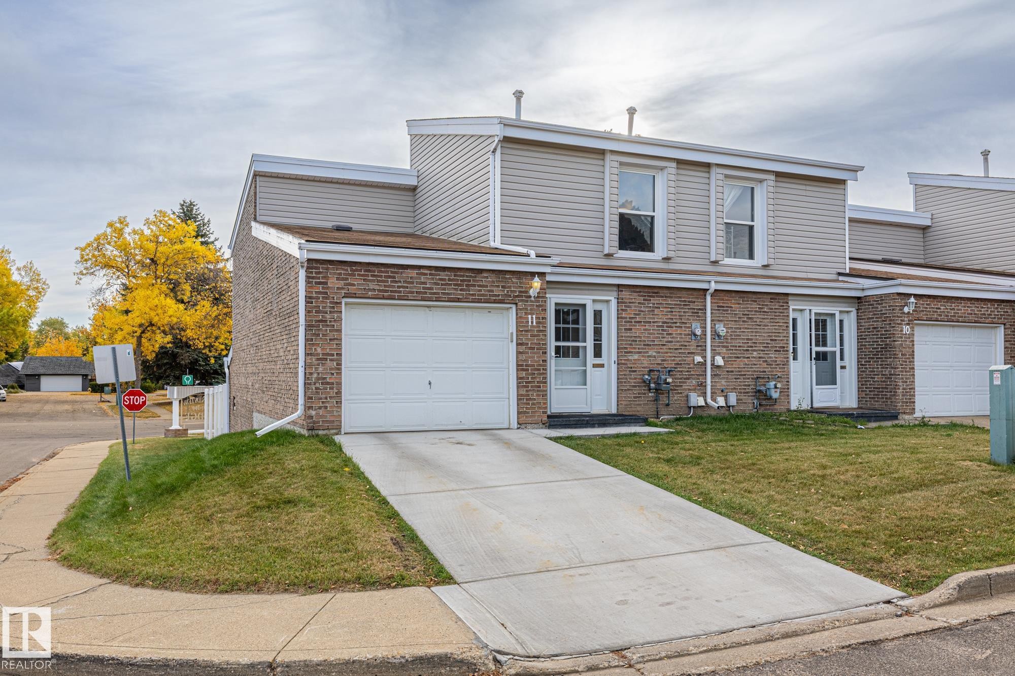 View of front facade featuring brick siding, driveway, a front yard, and an attached garage - 11 Grandview Ridge, St. Albert, AB - Outdoor With Facade