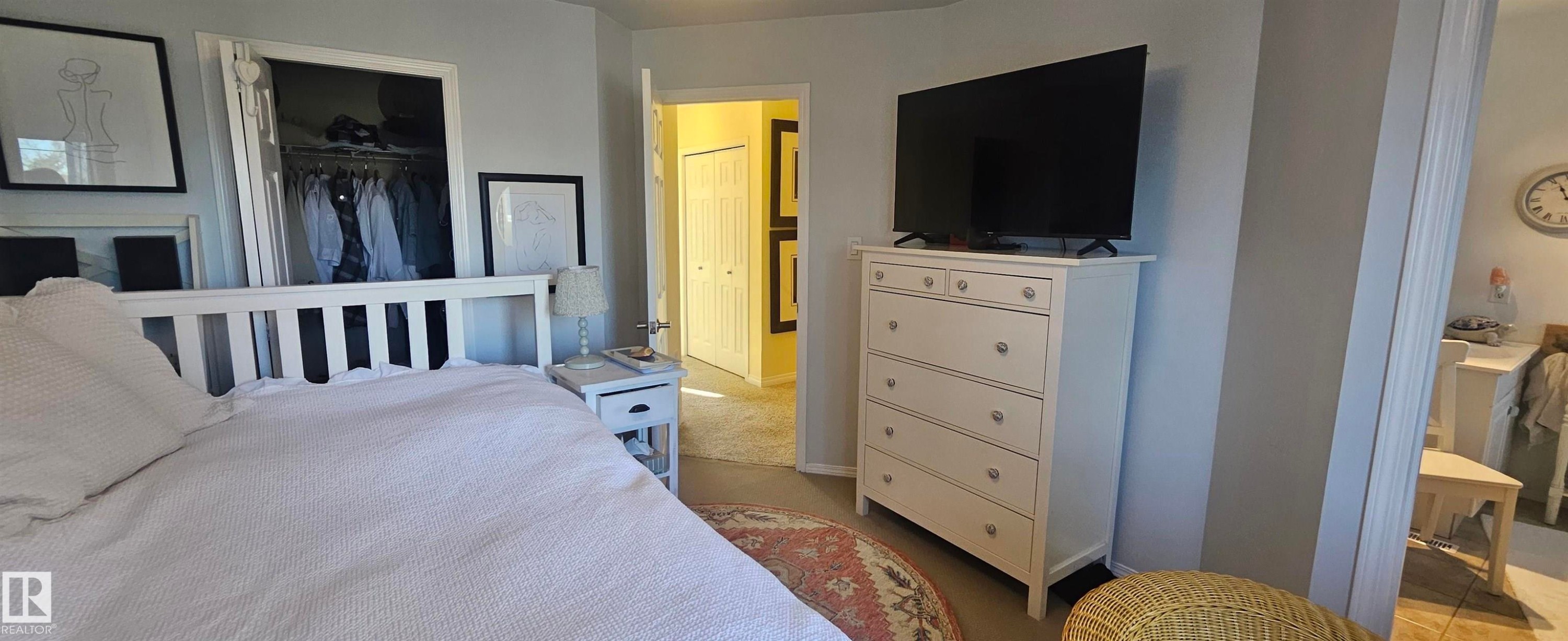 Bedroom featuring light carpet and a spacious closet - 208 178 Bridgeport Boulevard, Leduc, AB - Indoor Photo Showing Bedroom