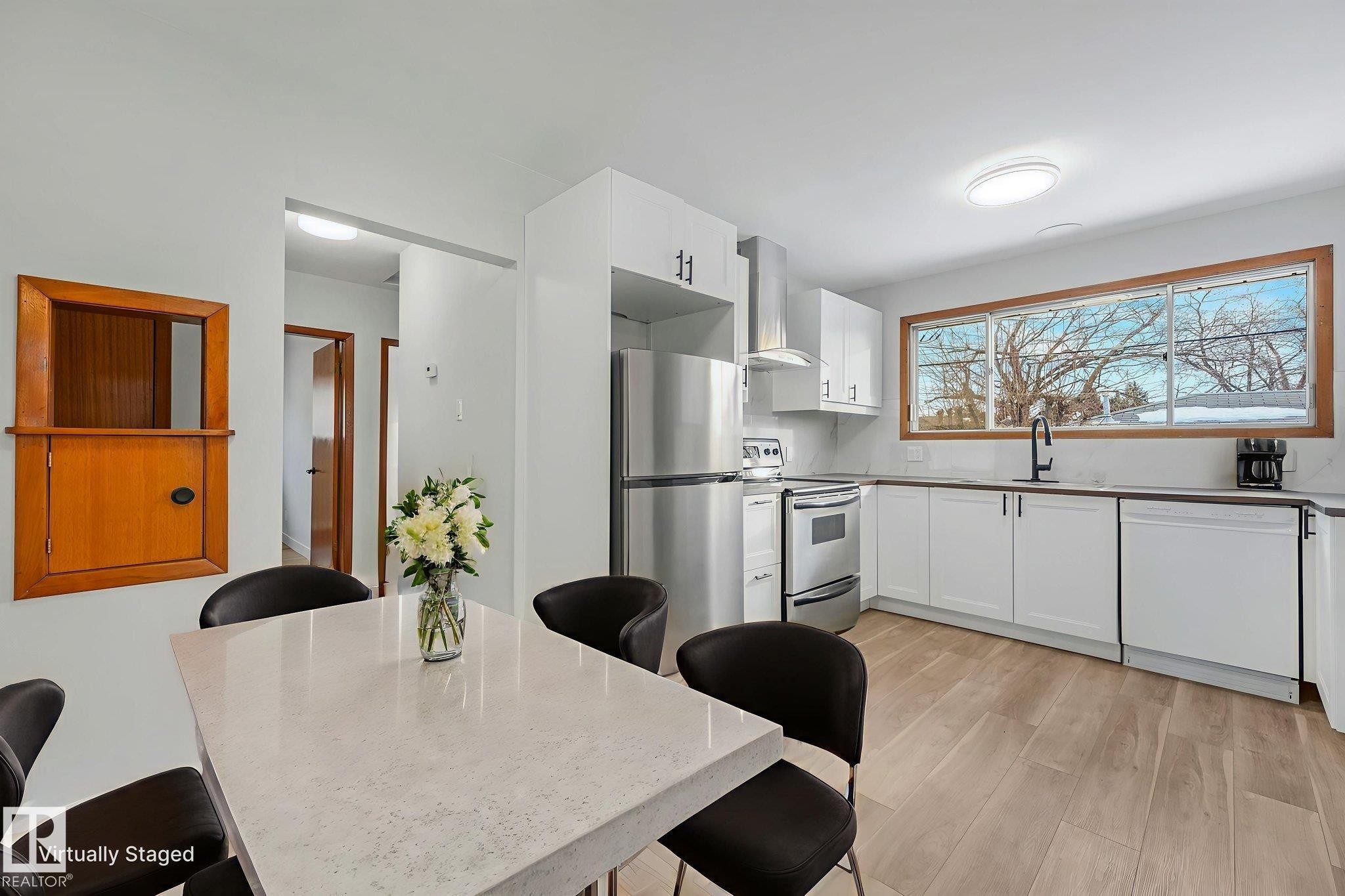 Kitchen with stainless steel appliances, white cabinetry, light wood-style floors, and a kitchen bar - 6007 95 Avenue, Edmonton, AB - Indoor