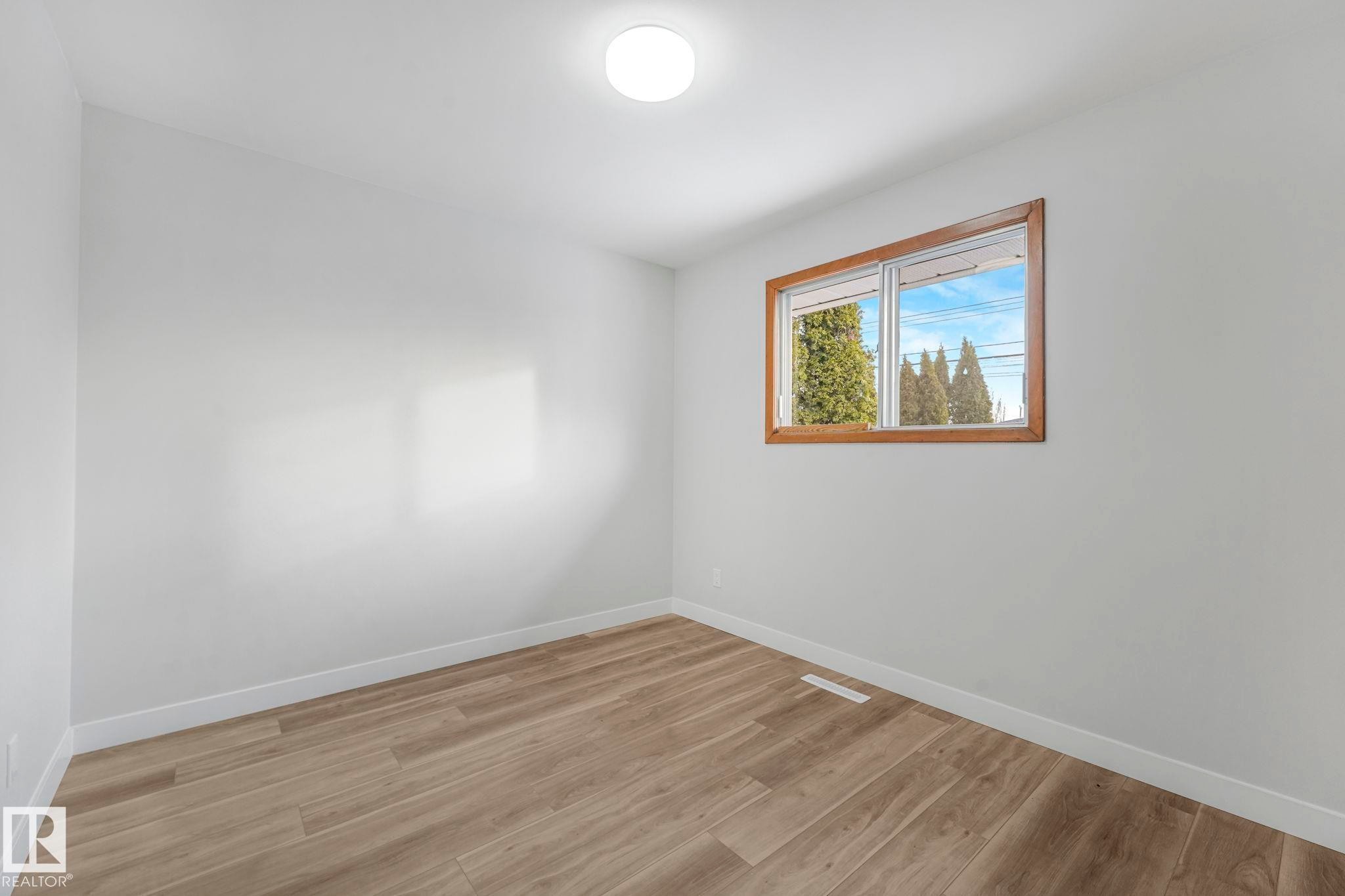 Empty room with light wood-type flooring and baseboards - 6007 95 Avenue, Edmonton, AB - Indoor Photo Showing Other Room