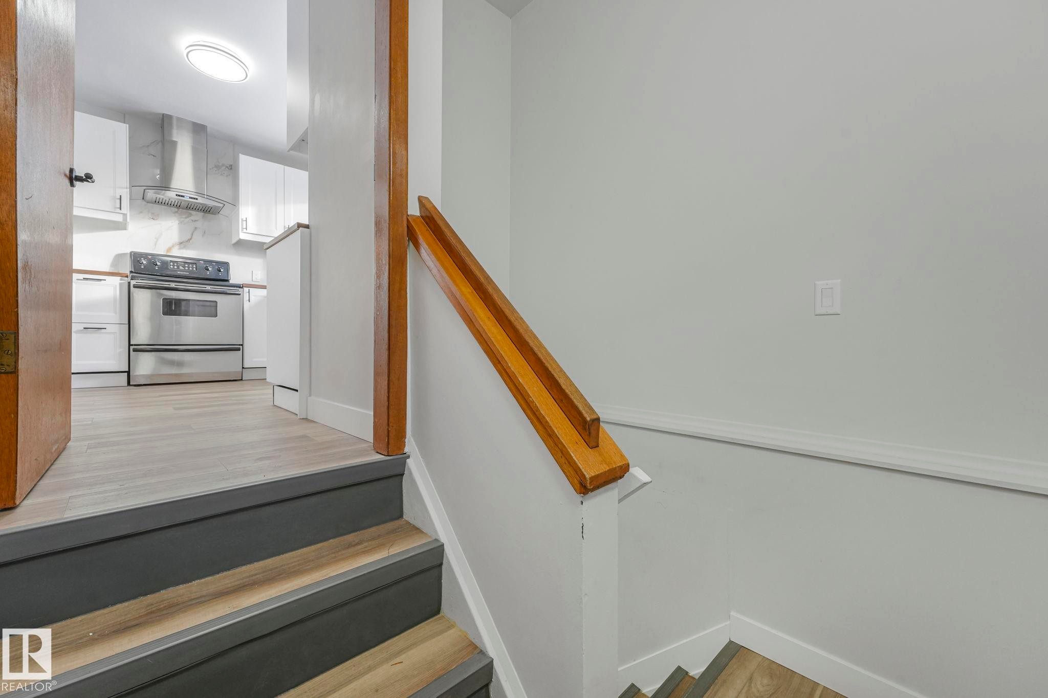 Staircase featuring wood finished floors and baseboards - 6007 95 Avenue, Edmonton, AB - Indoor Photo Showing Other Room