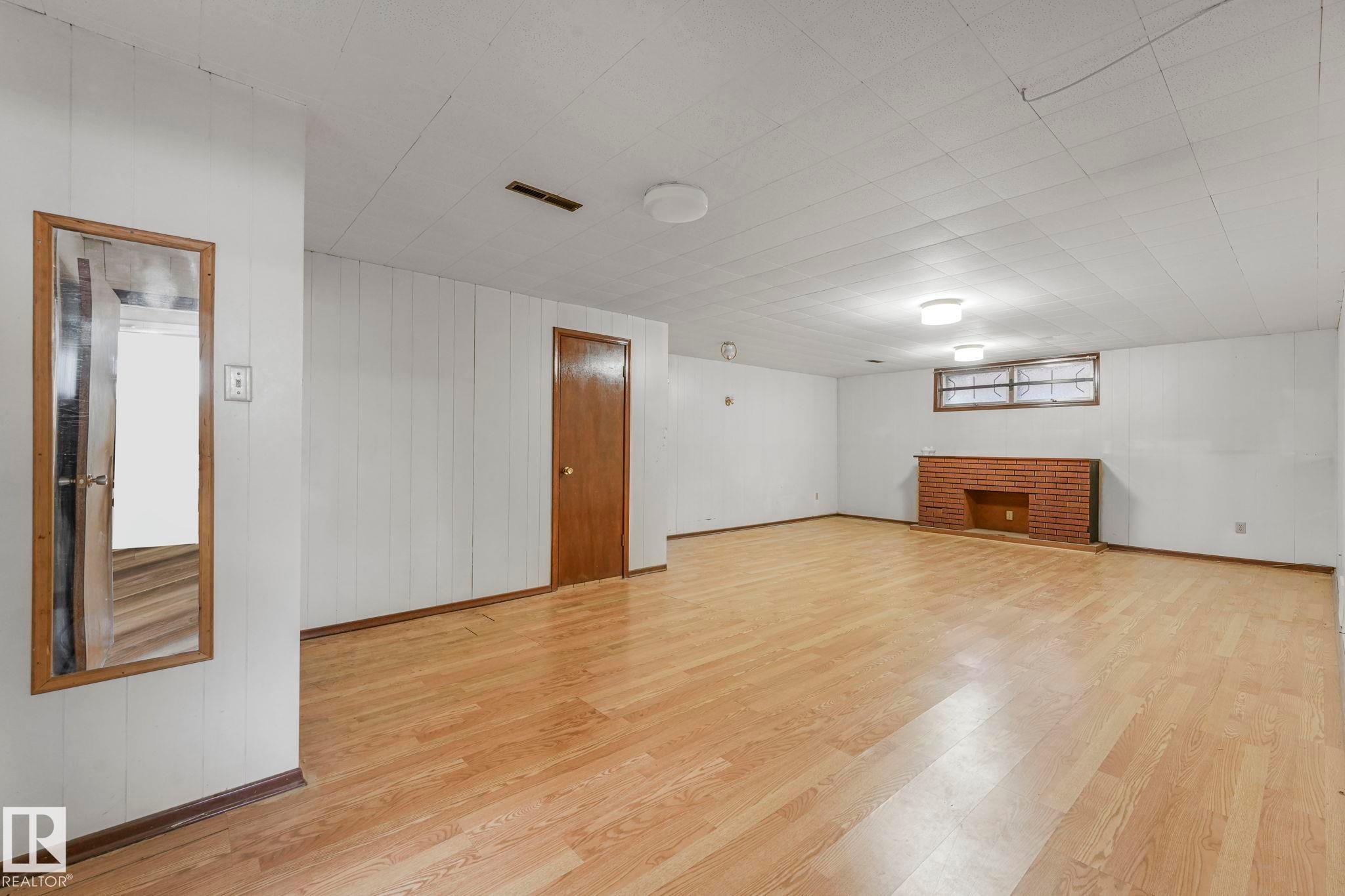 Unfurnished room featuring light wood-style floors and wooden walls - 6007 95 Avenue, Edmonton, AB - Indoor Photo Showing Other Room